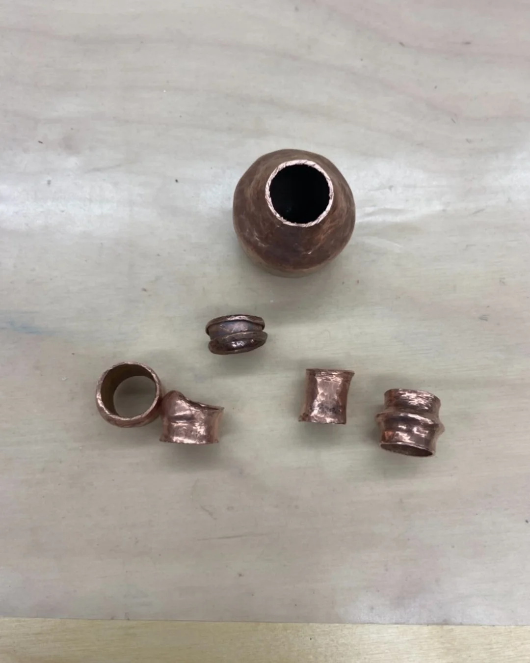 Ore Metals Studio instructor Jana shows how she takes a flat sheet of metal, raises it into a vessel with a narrow top, then turns it into seamless rings, and the base into a monster head ring jar. Because she hates wasting metal, she continues and m