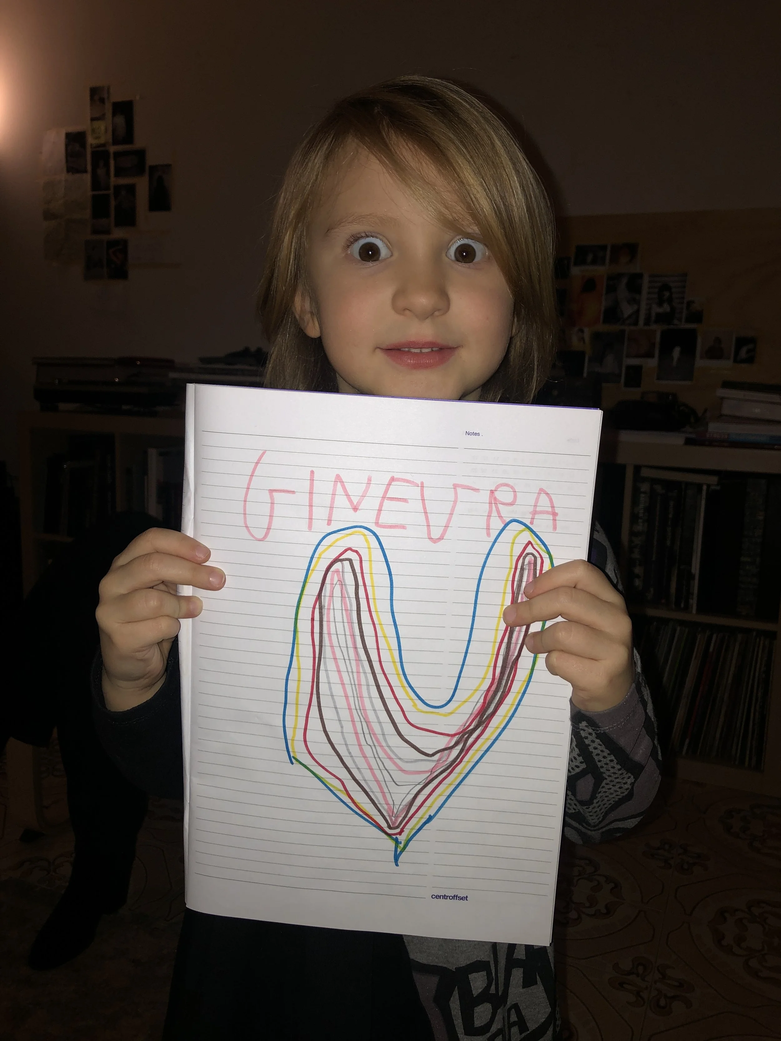 Bambina che tiene un foglio con disegno di cuore e nome "Ginevra"