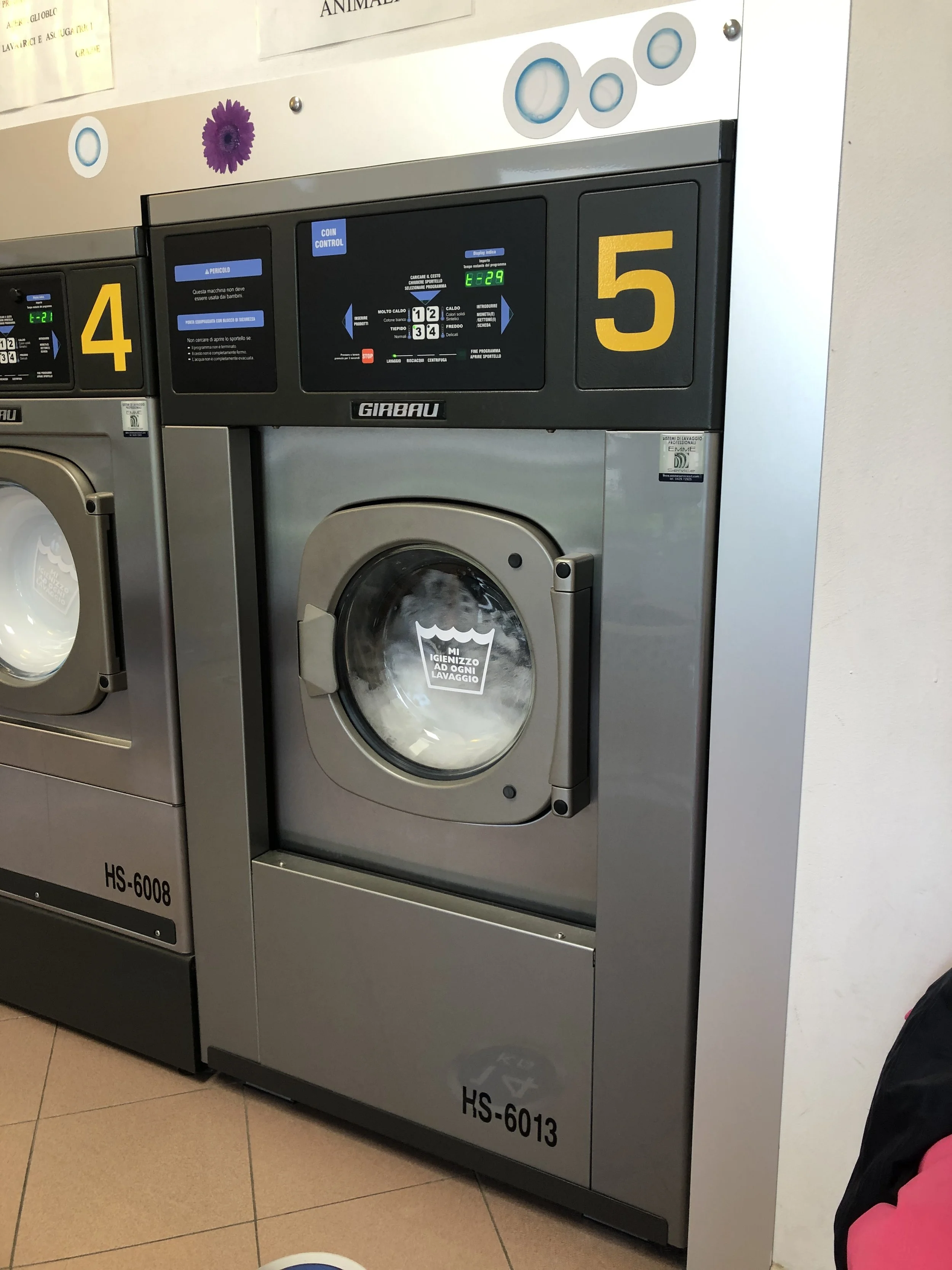 Lavatrici industriali numerate, una con il numero 5 in un locale lavanderia.