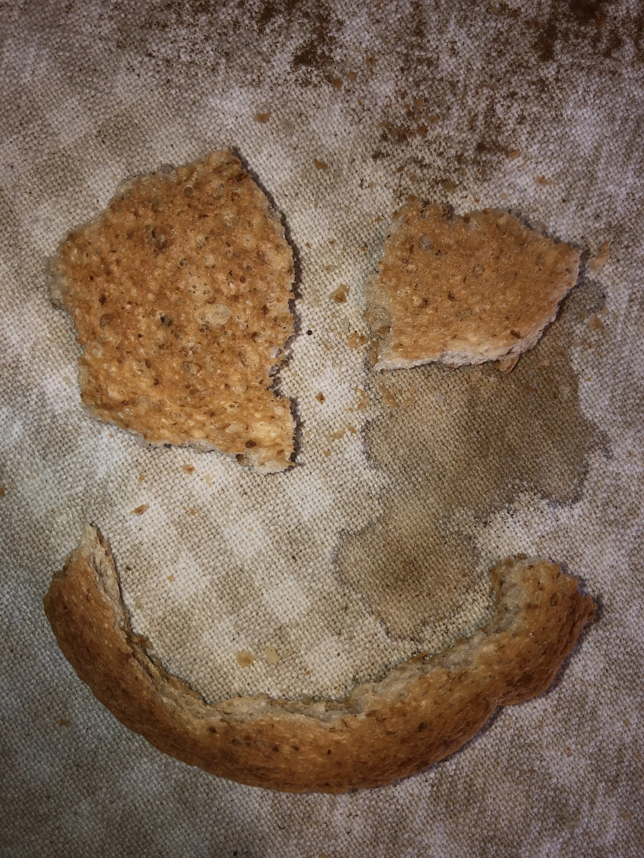 Pezzi di pane disposti a formare un volto sorridente su una superficie chiara.