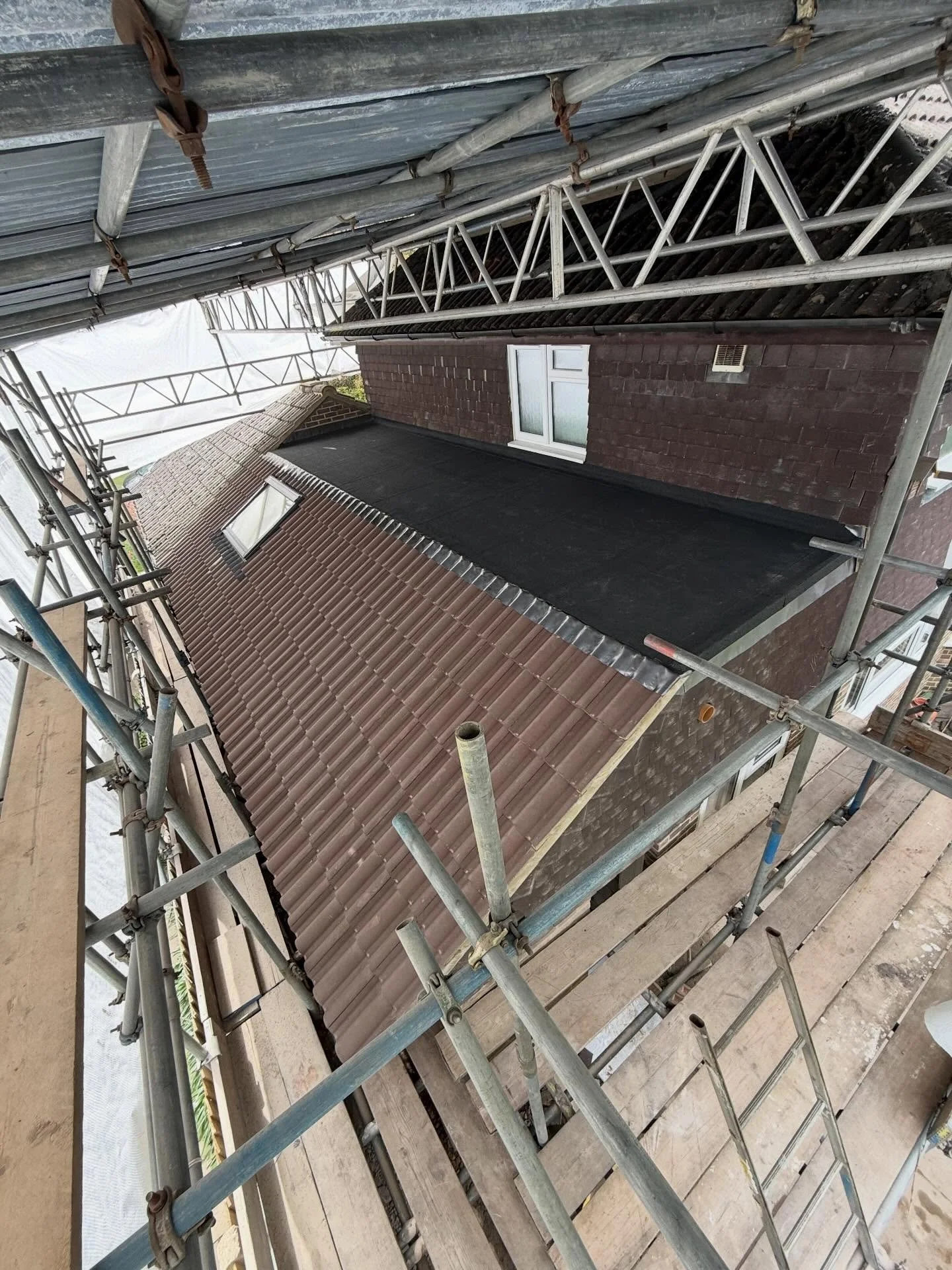 Roof on a new extension we recently completed in Oxshott Surrey. We used Redland Regent concrete interlocking tiles to pitch roof, we used a 3 layer torch on felt system to crown flat roof and Redland 02 brown concrete plain tiles to vertical. Visit 
