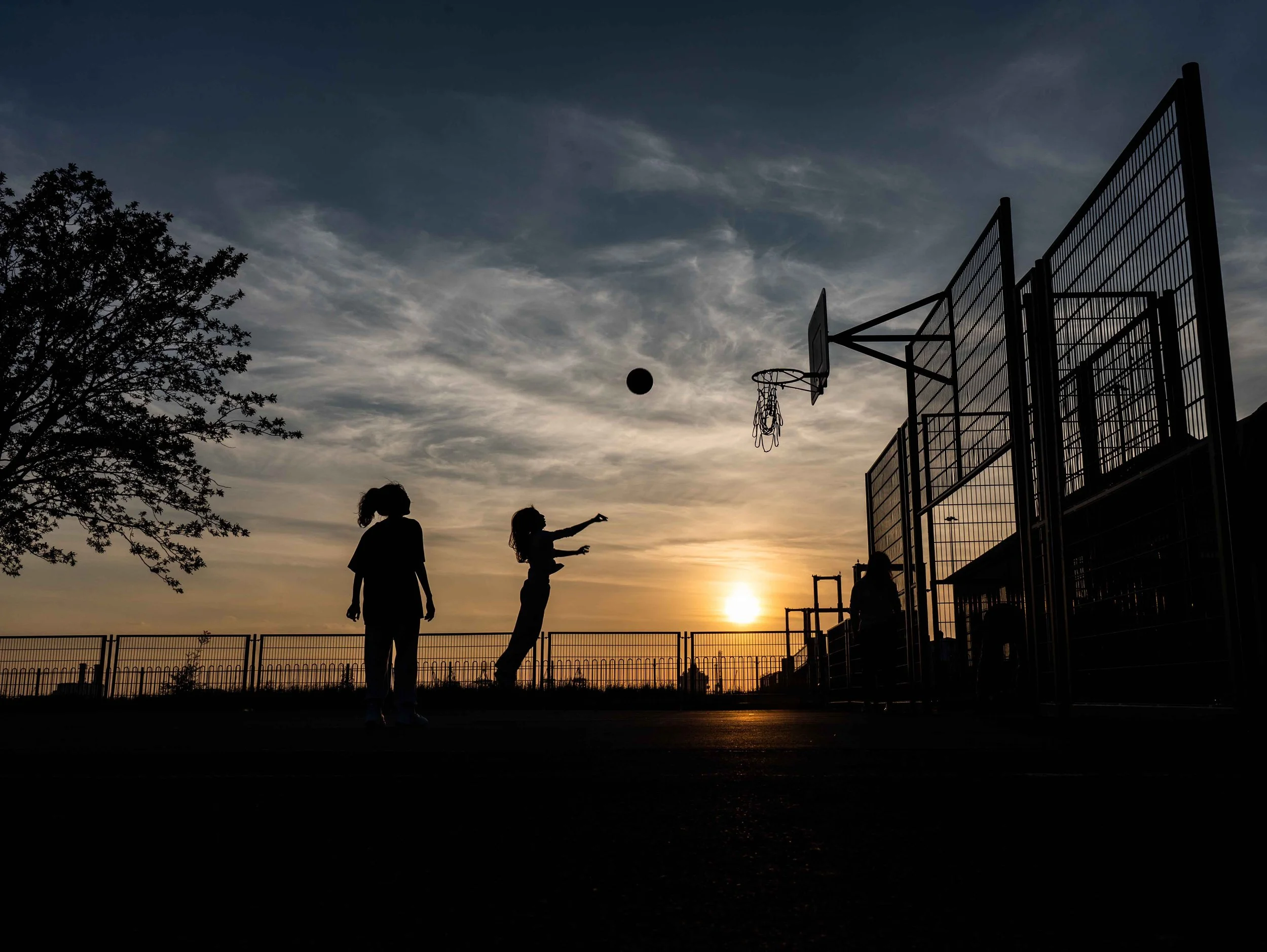 people playing basketball during sunset