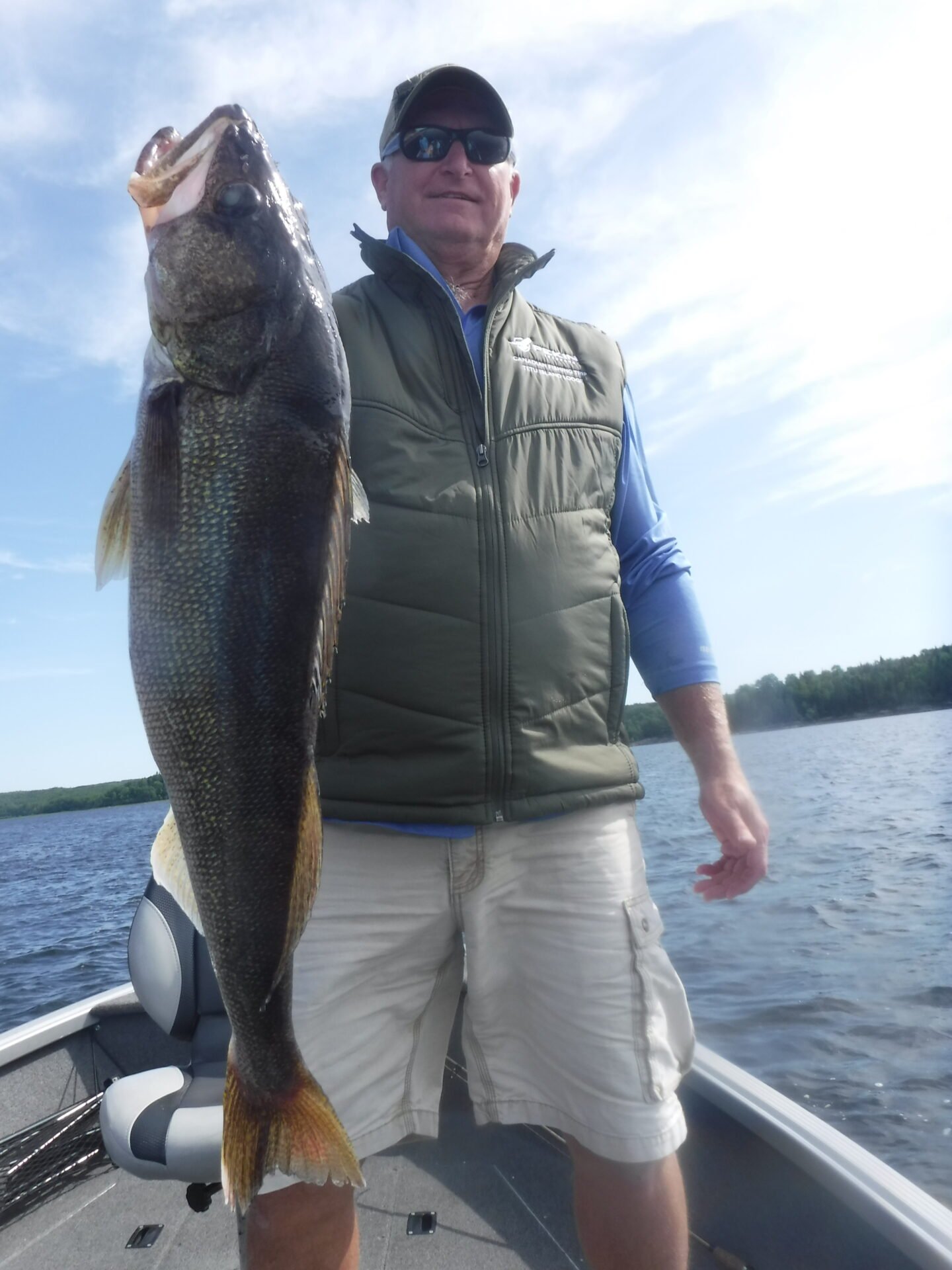 Person holding a large fish on a boat in a lake