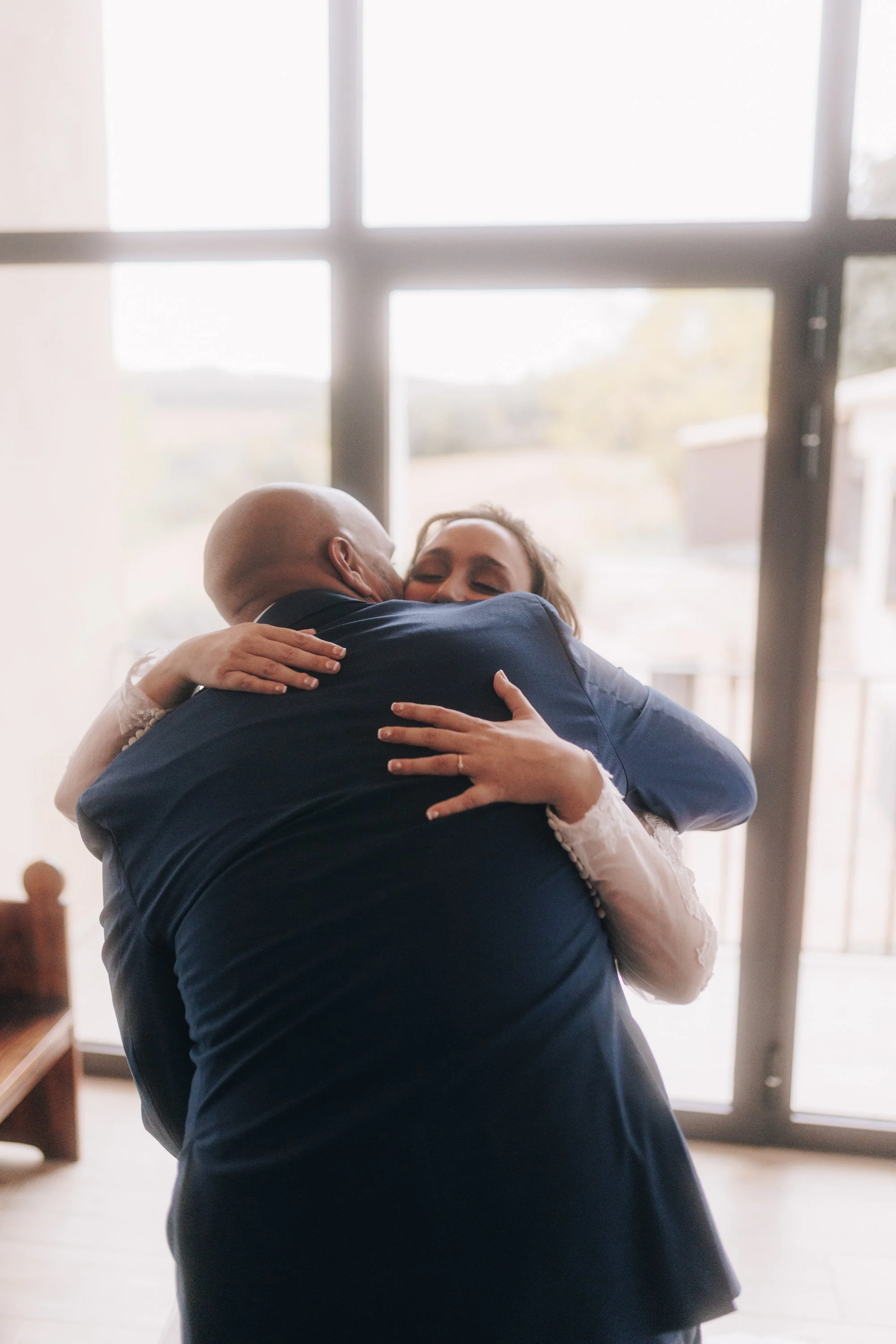 Retrato emotivo de novia abrazando a su hermano durante los preparativos