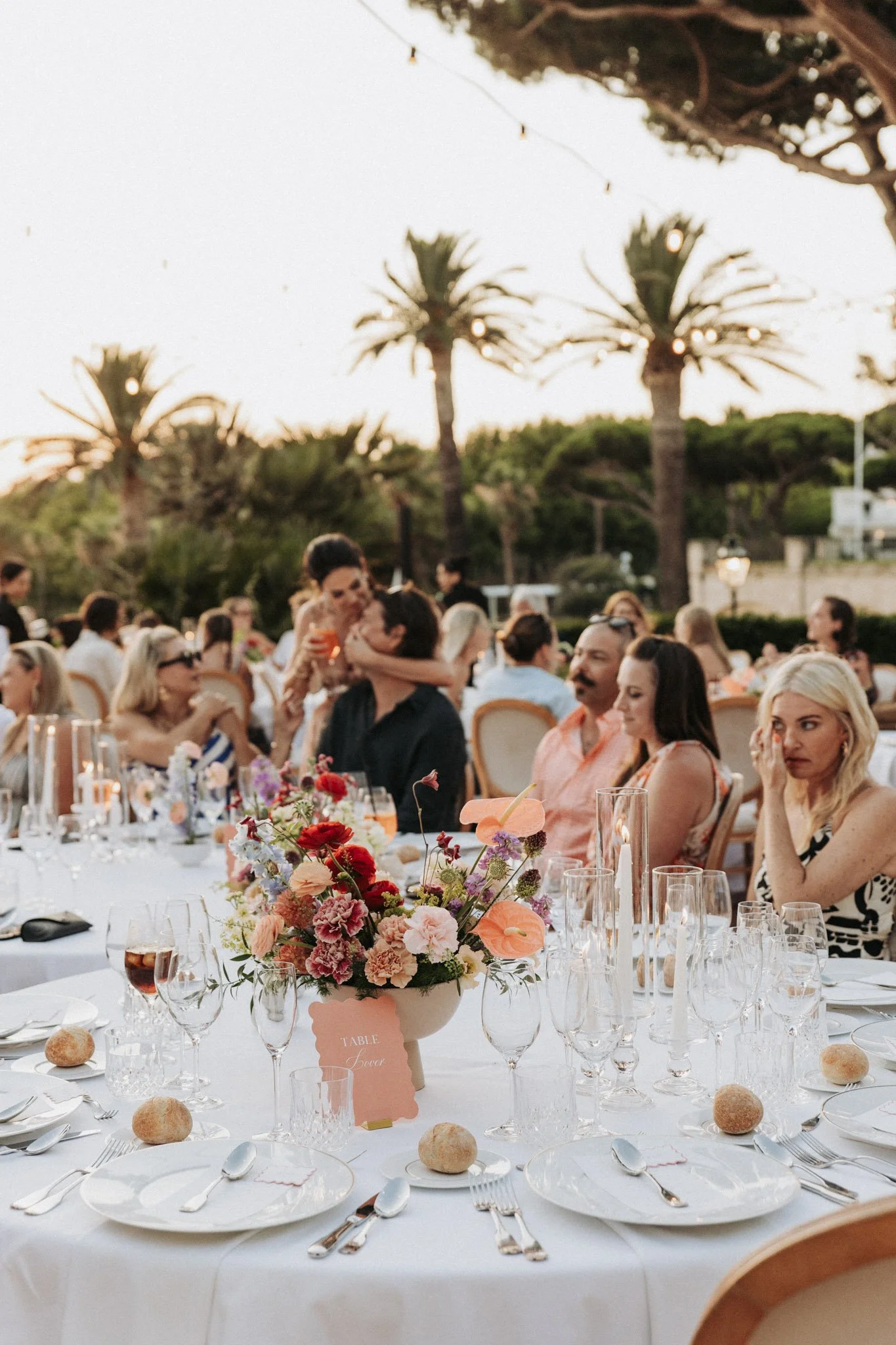 candid-portrait-of-wedding-guests-at-dinner-with-table-flower-decor-mas-terrats-girona-destination-wedding-photographer.jpg