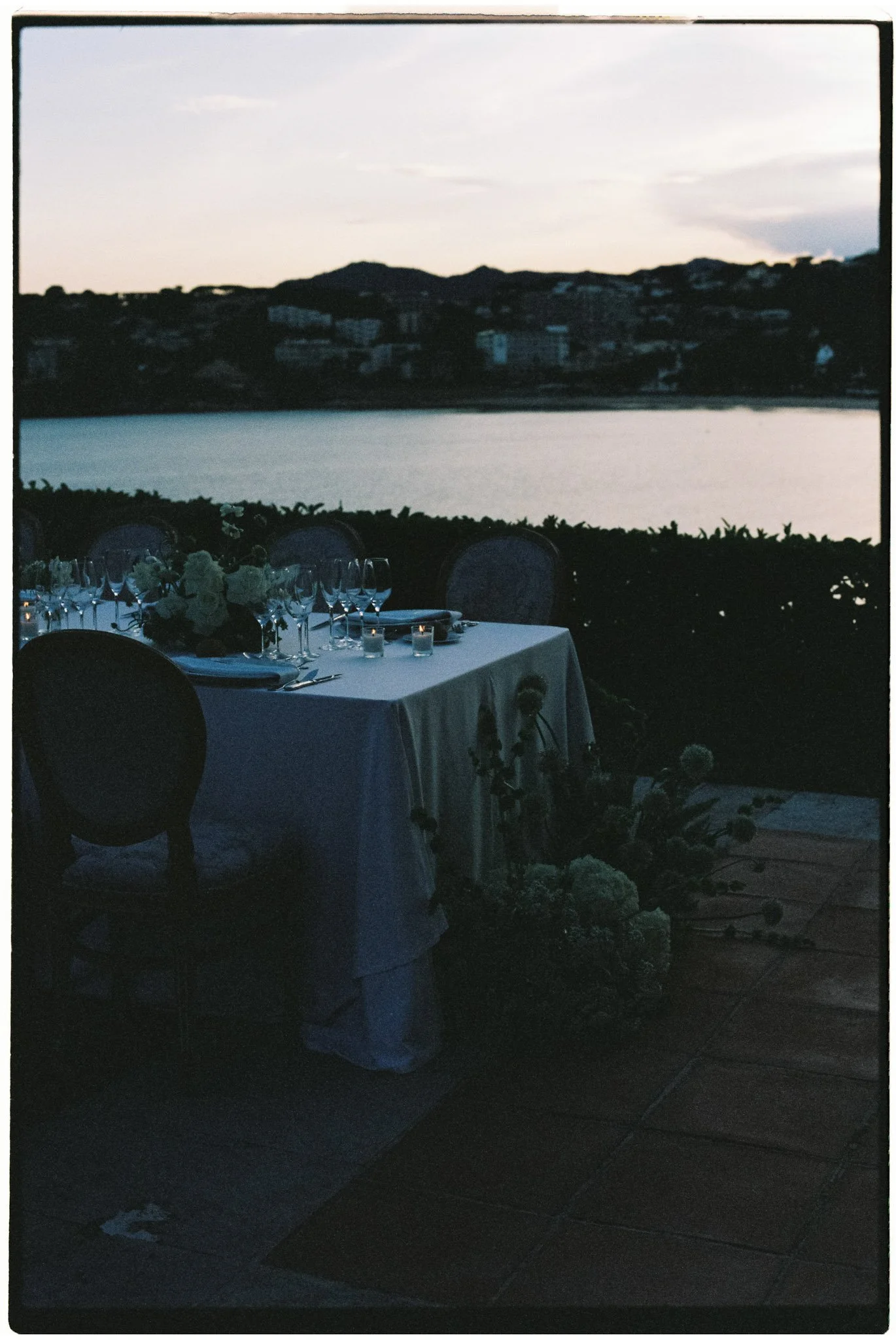 Dinner bridal table next to the sea under the light of the sunset with candles and floral arrangements