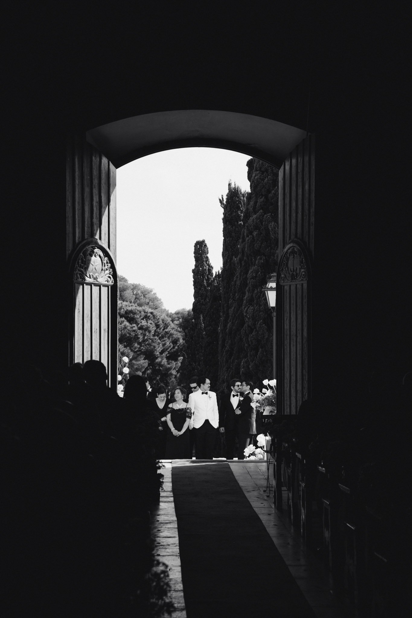 editorial-shot-of-groom-in-church-door-before-catholic-ceremony-la-cartuja-de-ara-christi-valencia-destination-wedding-photographer.jpg