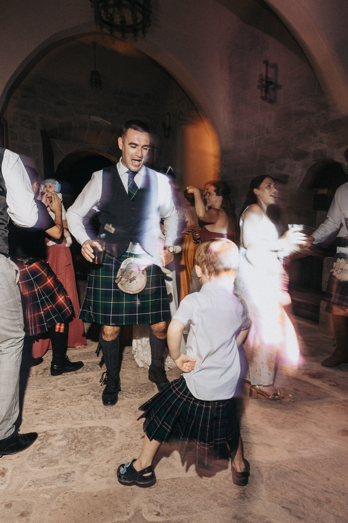 fun-portrait-of-wedding-guests-dancing-at-party-in-scottish-traditional-kilt-castell-d-enfesta-barcelona-destination-wedding-photographer.jpg