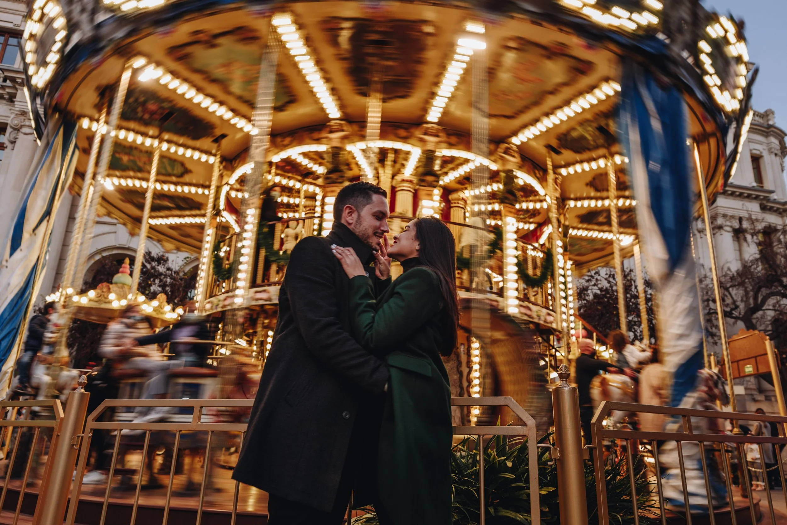 Pre-wedding couple portrait in the city in front of a moving carousel.