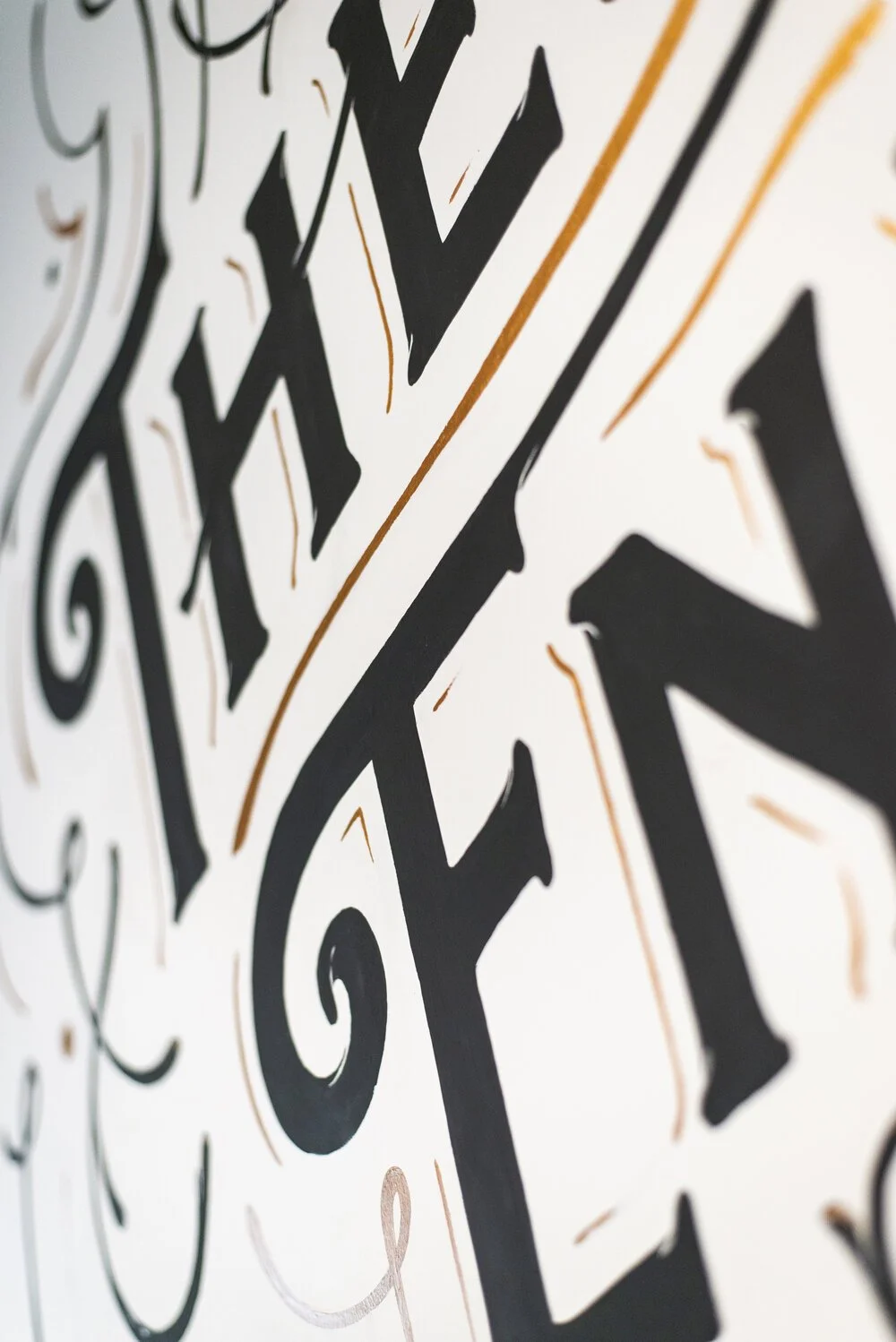 Close-up of decorative black and gold lettering on a white background.