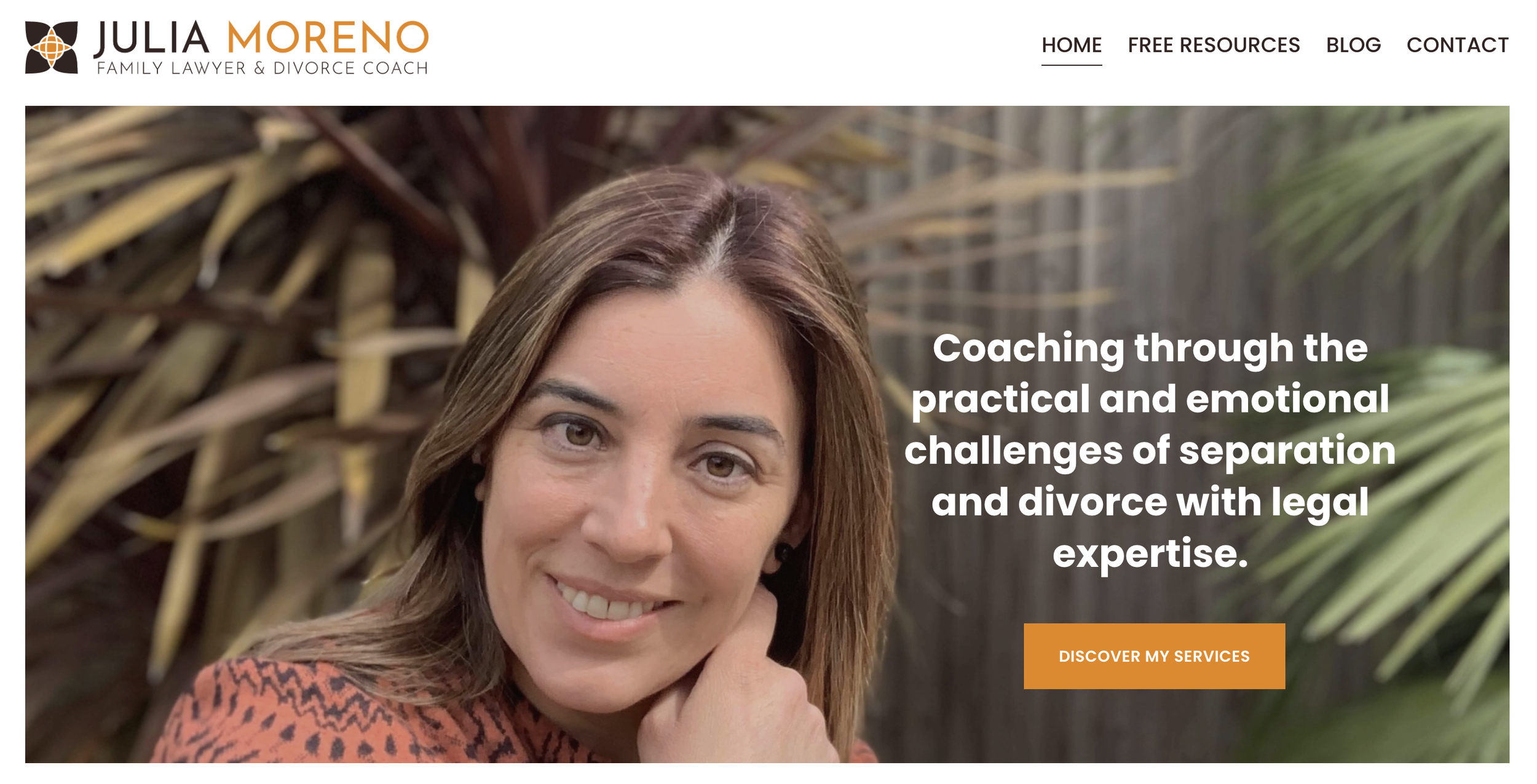 Portrait of Julia Moreno, family lawyer and divorce coach, smiling with her hand resting on her chin, in front of a background with green and brown foliage.