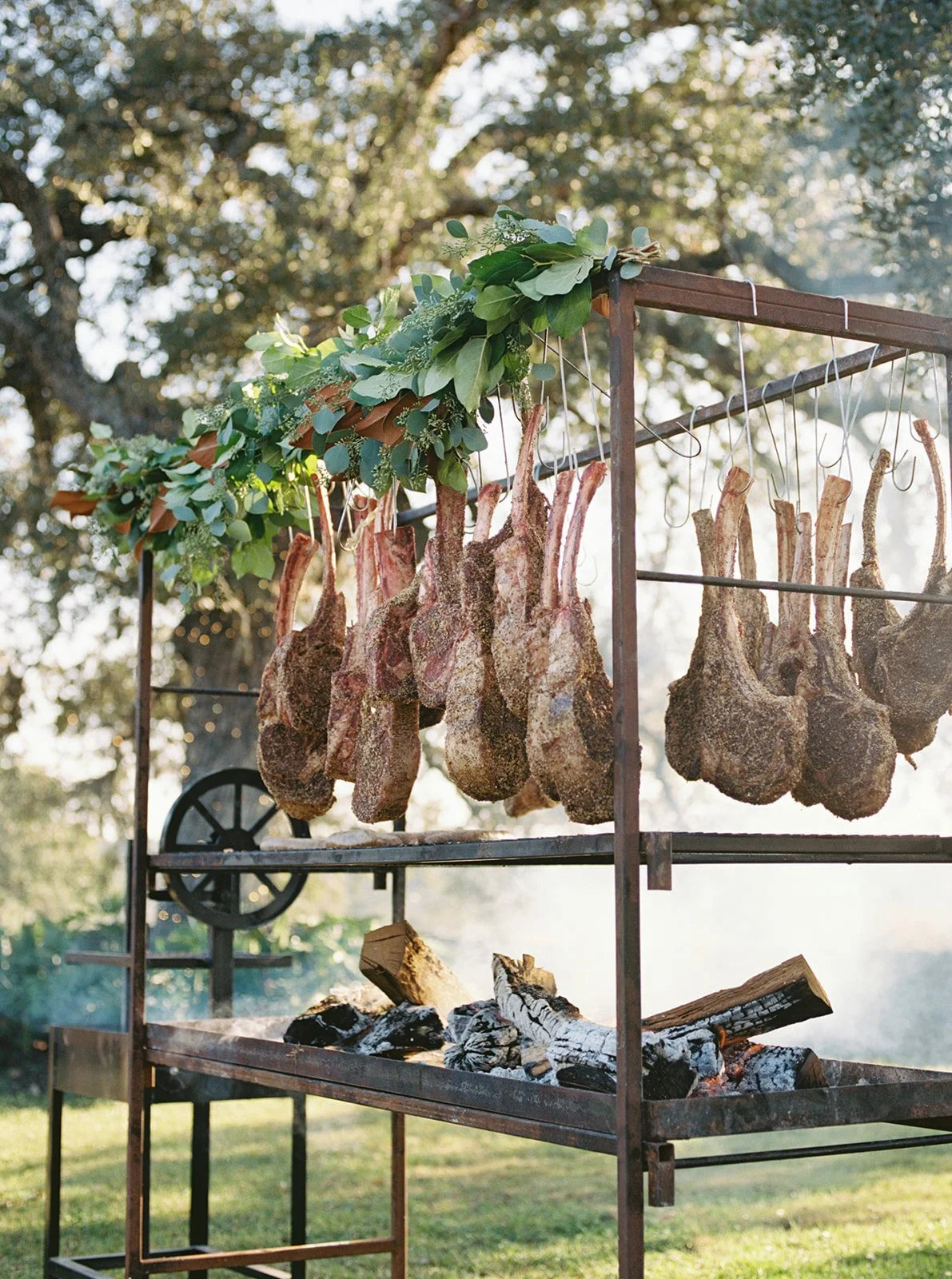 Gold Epicure hanging ribeyes over a live wood fire at a Central Texas wedding