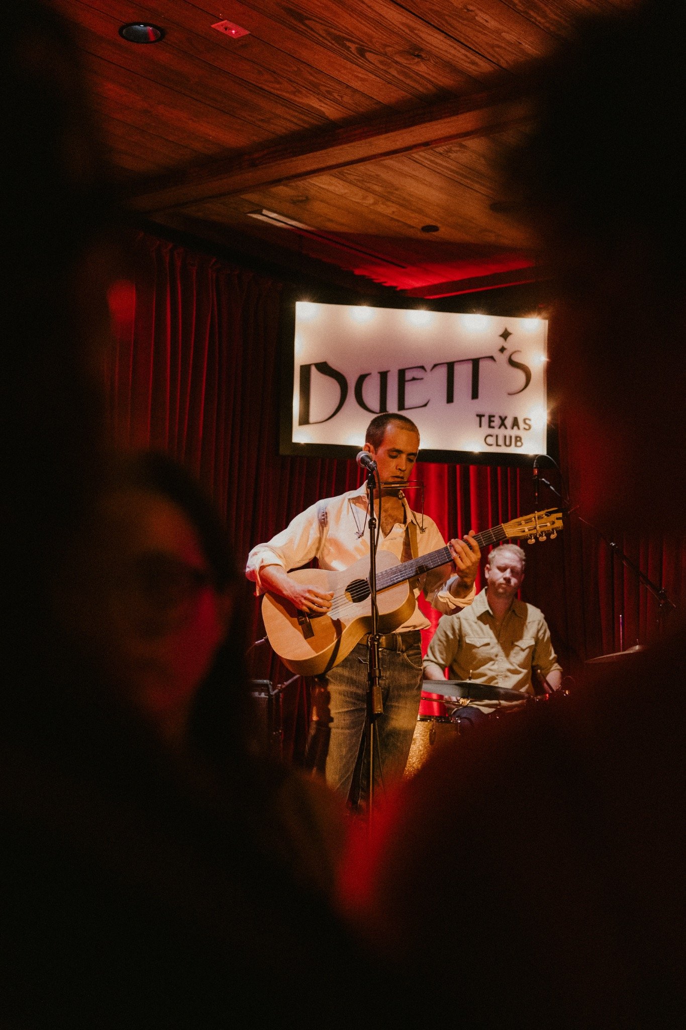 Live music on stage beneath the Duetts Texas Club sign in Martindale, Texas.