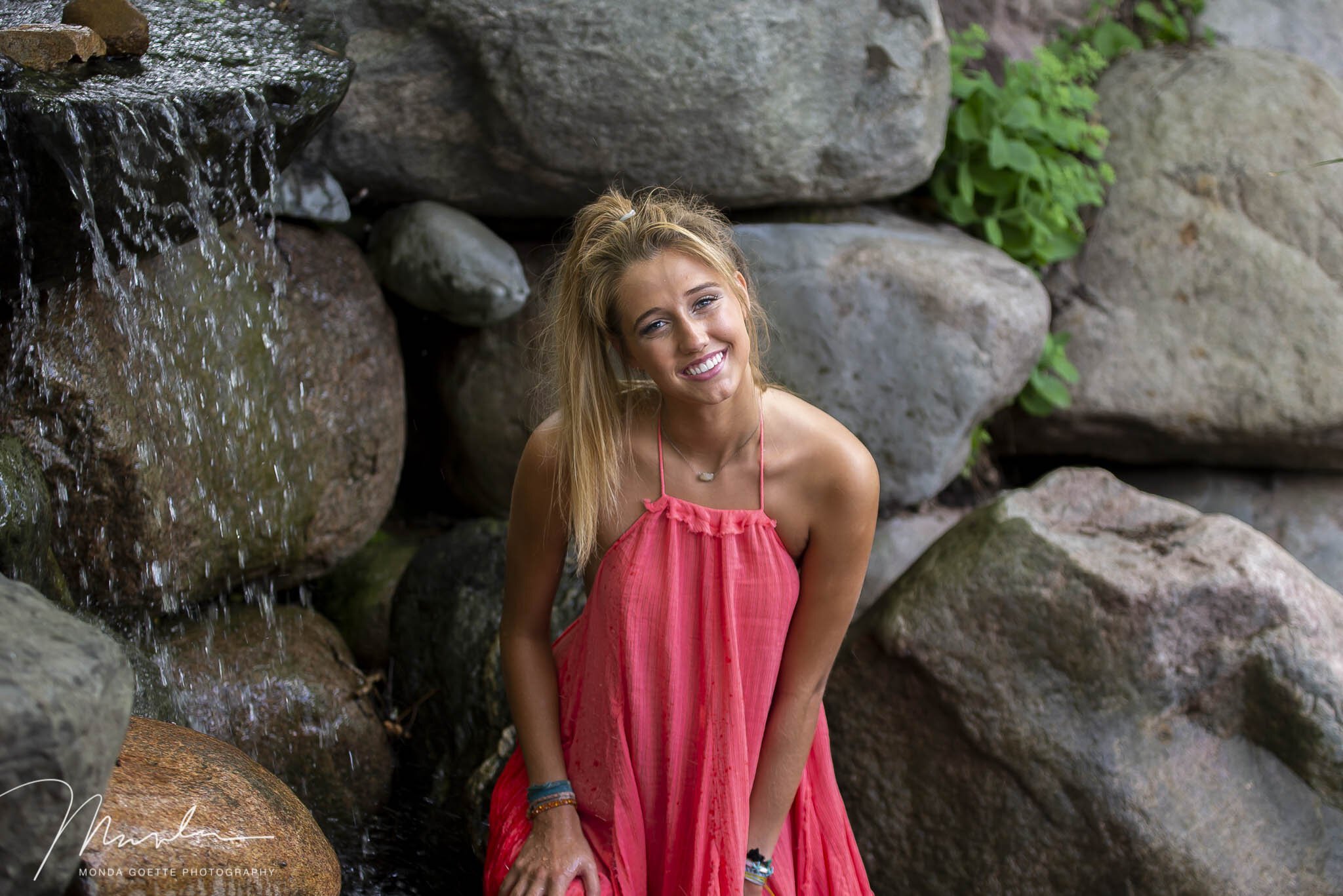 Senior girl near waterfall wearing a coral dress in the Twin Cities.