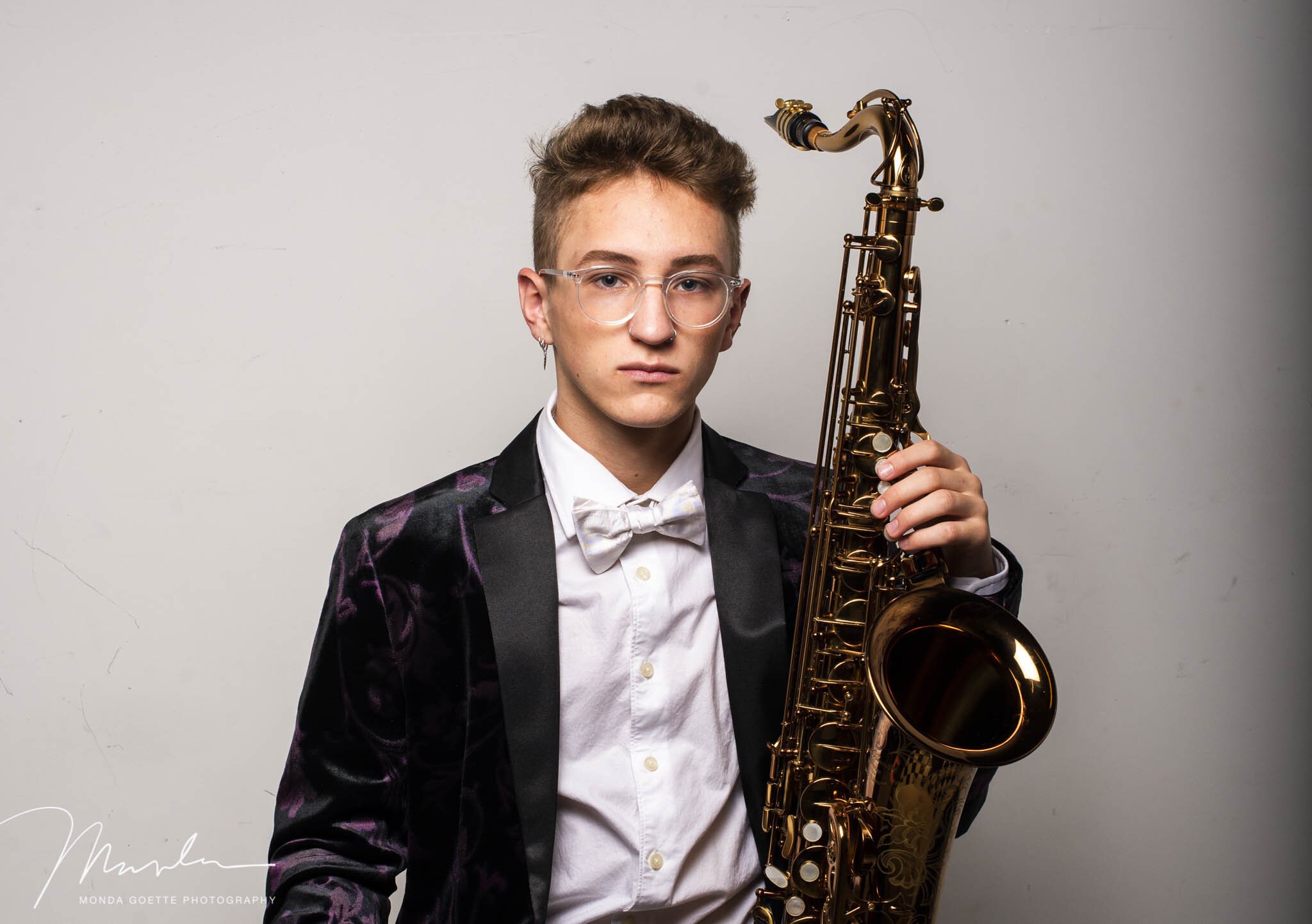 senior guy with glasses holding his saxophone during photo shoot at Monda Goette Photography