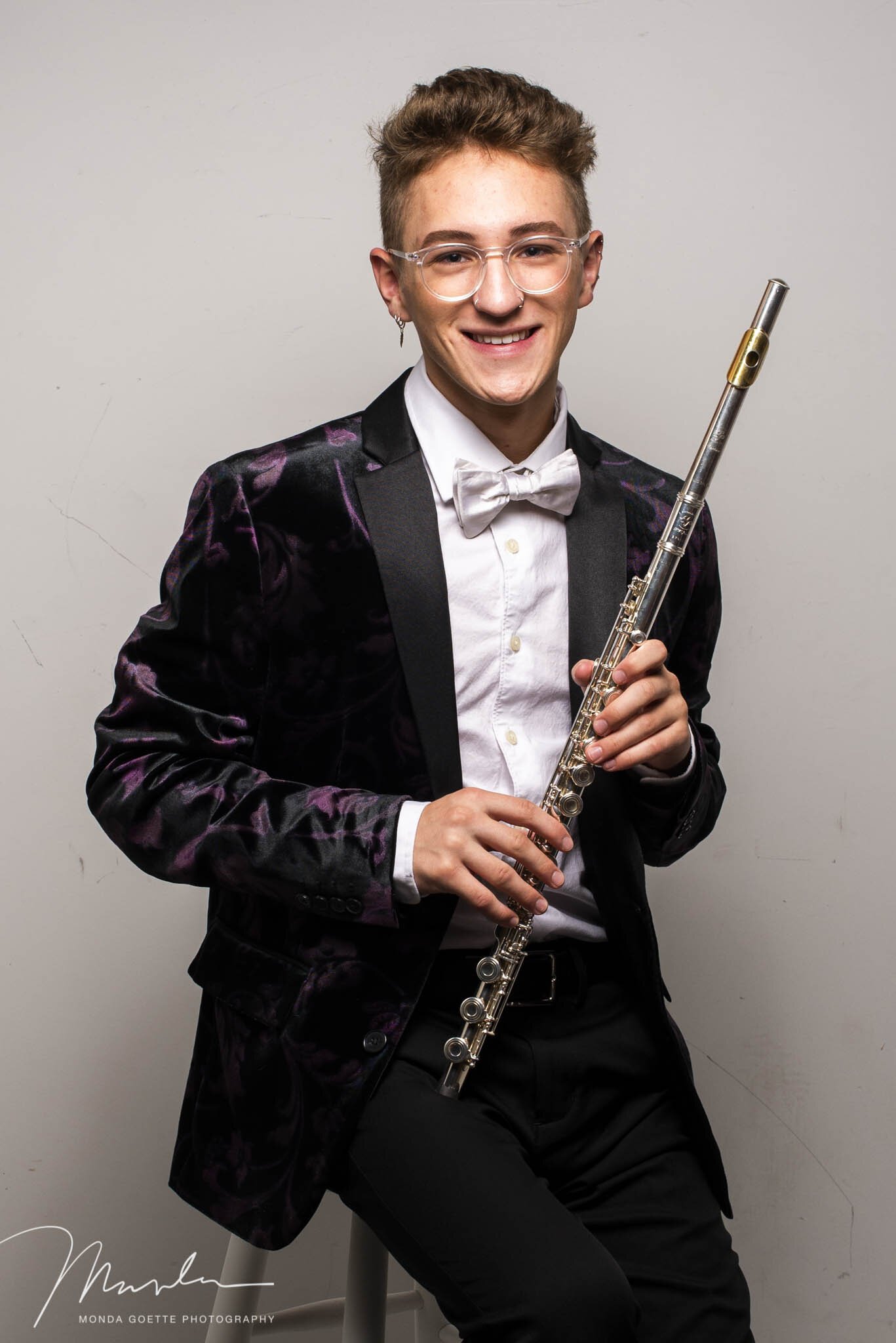 Class of 2021 stylish senior guy sitting on stool with his flute for a portrait