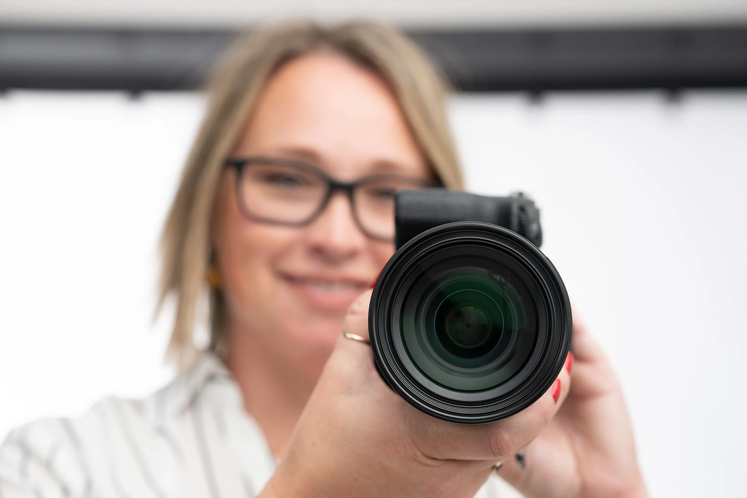 Monda Goette Photography holding a camera with the lens in focus, representing intentional visibility and clarity in branding.