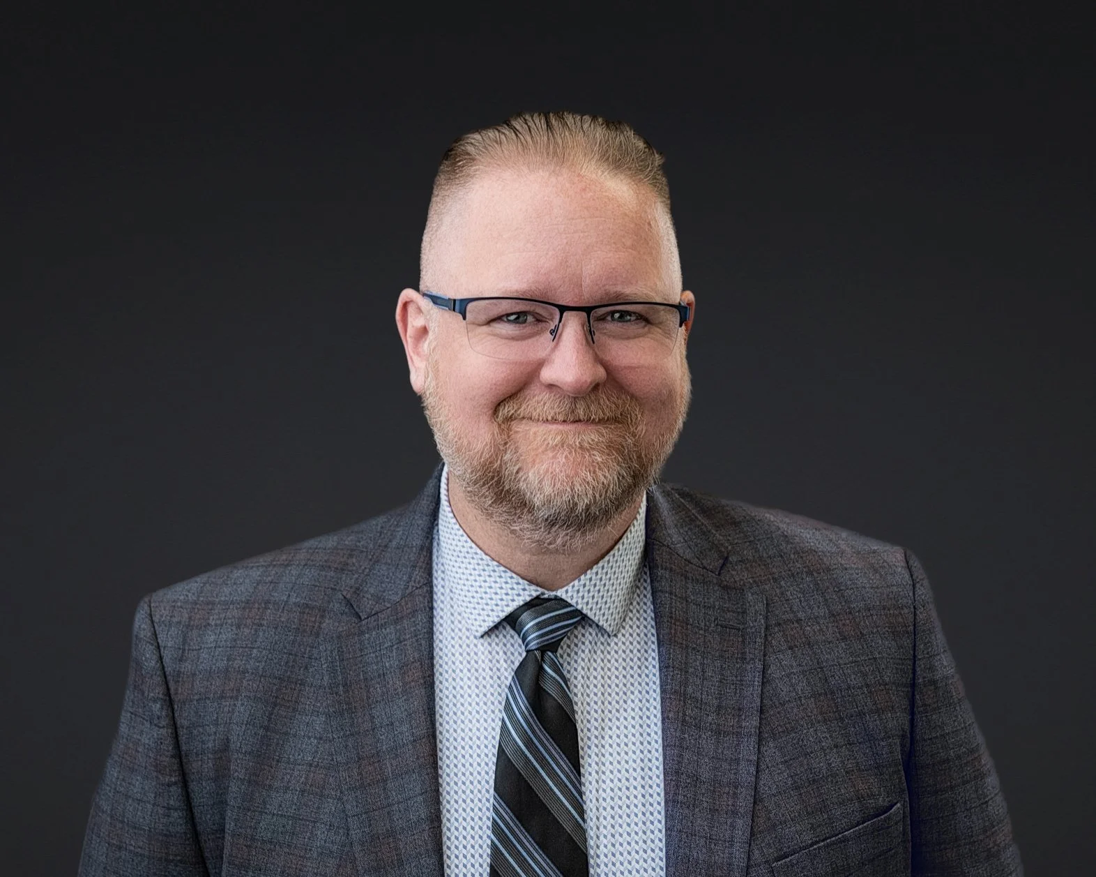 Male wearing suit and tie for a portrait on a dark grey backdrop