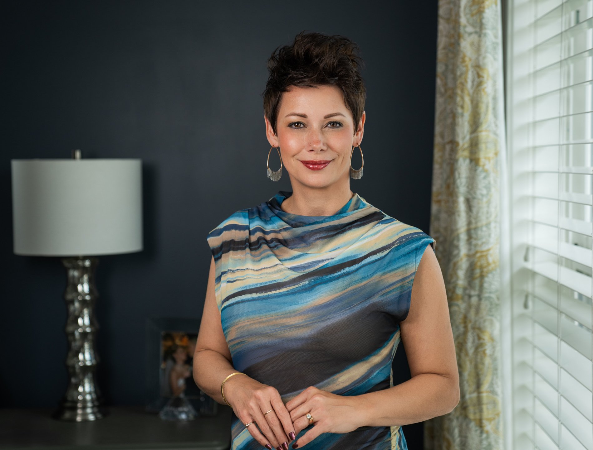 Personal branding imagery of a woman wearing a patterned dress near a window.