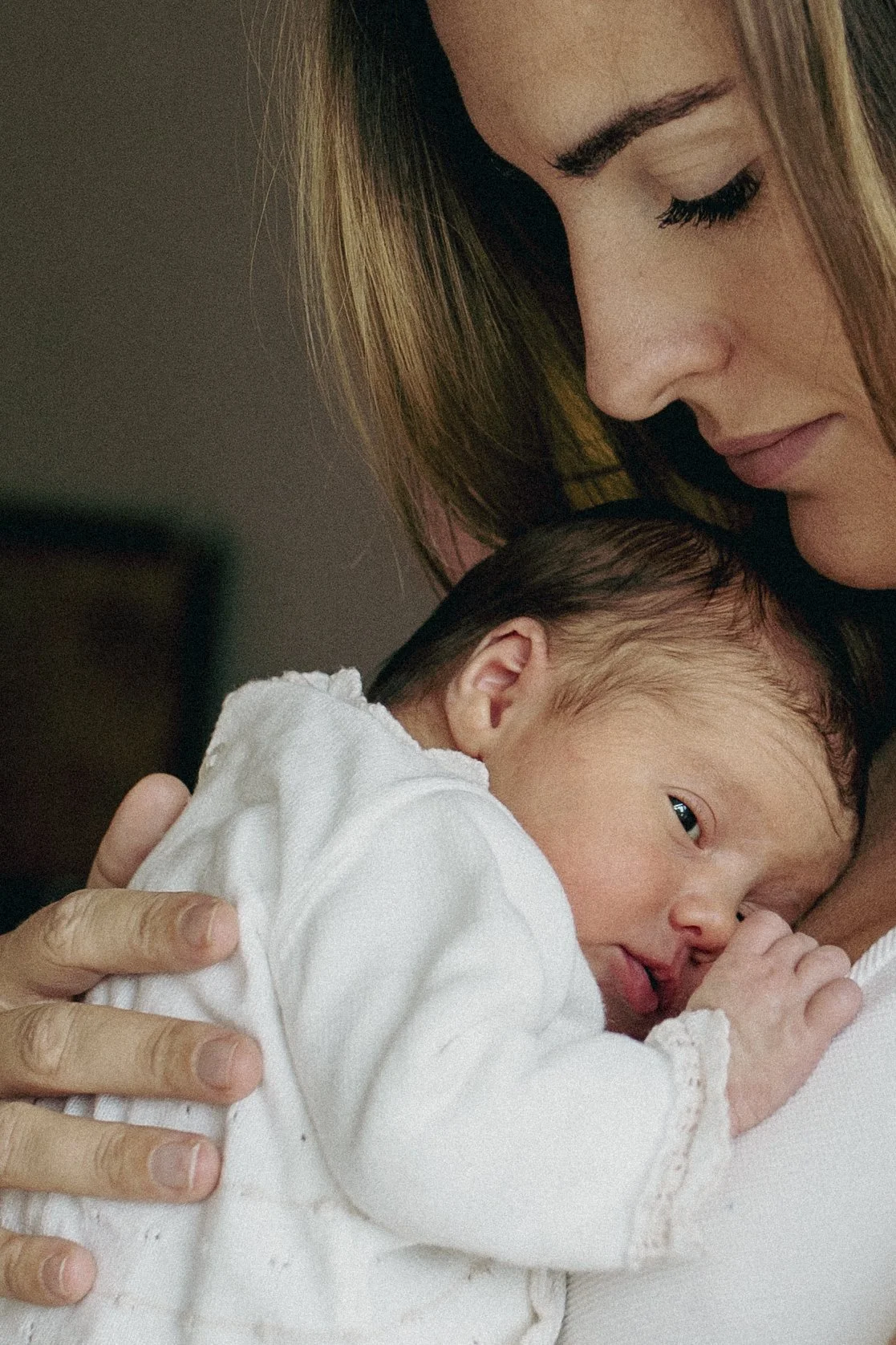 A woman tenderly holding a newborn baby close to her chest.