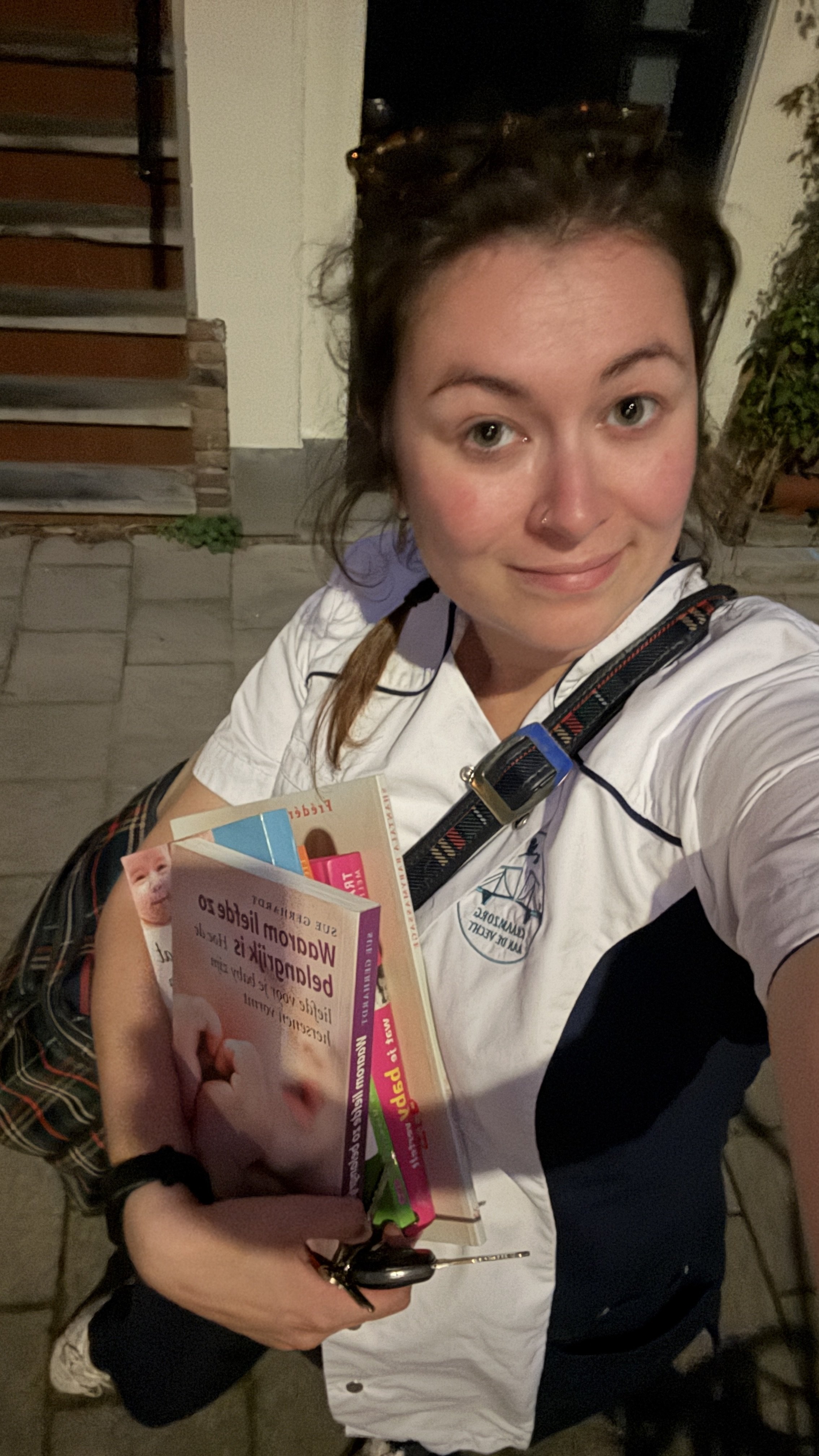 Een vrouw in een wit en blauw uniform houdt een boek en een stuk papier vast, terwijl ze buiten staat bij nacht.