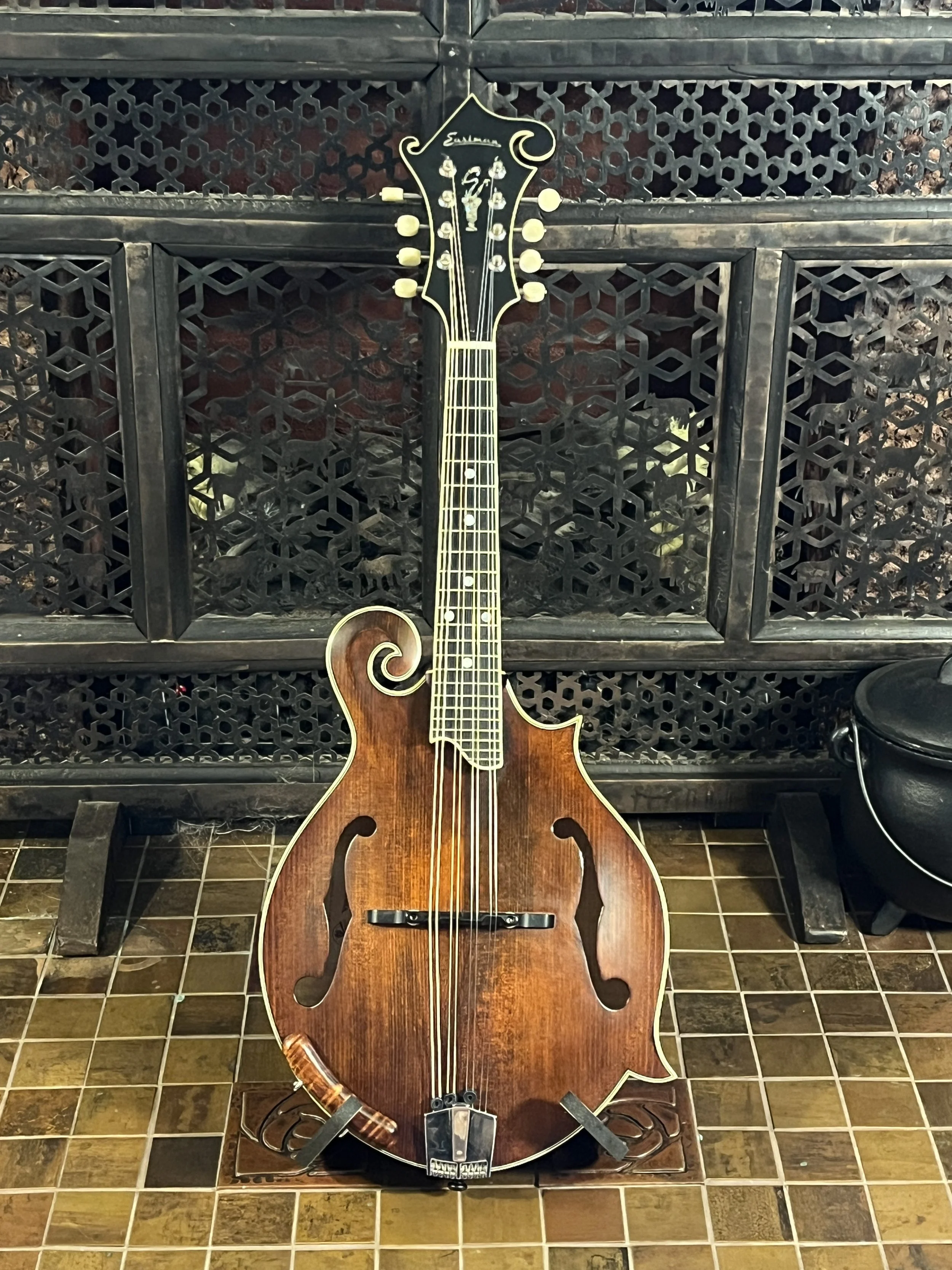 Eastman 715 Mandolin sitting on a display stand, pictured from the front, showing f-holes, scroll & fingerboard. (2024, #6 of 15, original run)