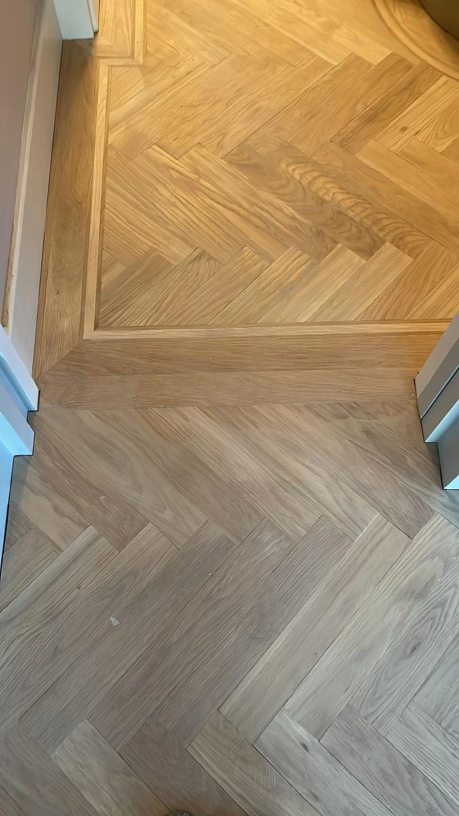 Close-up of a hardwood floor with a detailed transition strip between two different wood patterns.