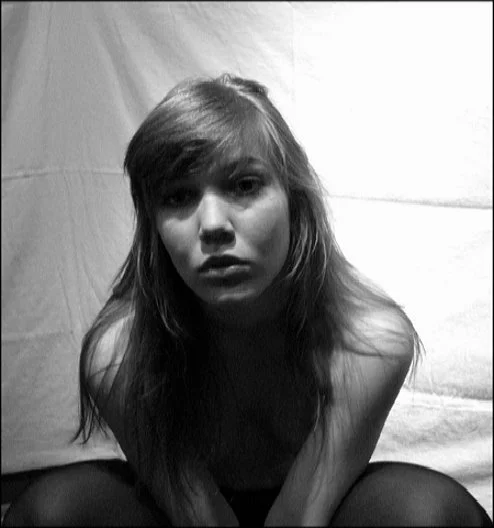 Seated self-portrait against fabric backdrop, black and white