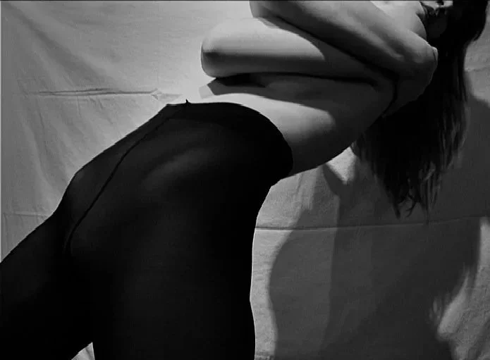 Black and white self-portrait emphasizing elongated body lines and shadow, focusing on form, movement, and physical expression.