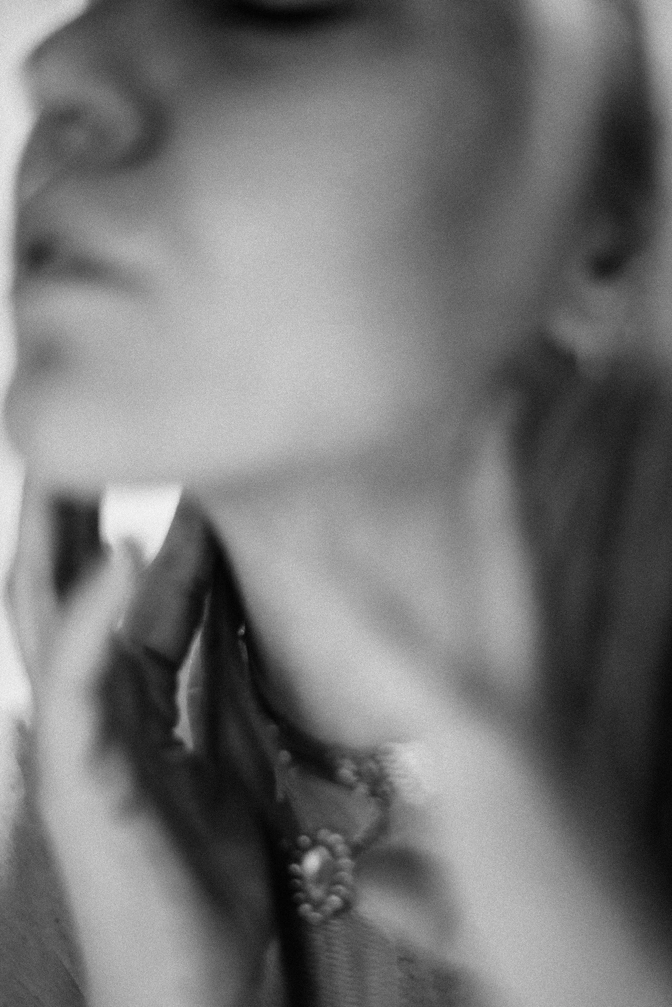 Abstract black-and-white portrait with hand touching neck, captured in soft motion blur.
