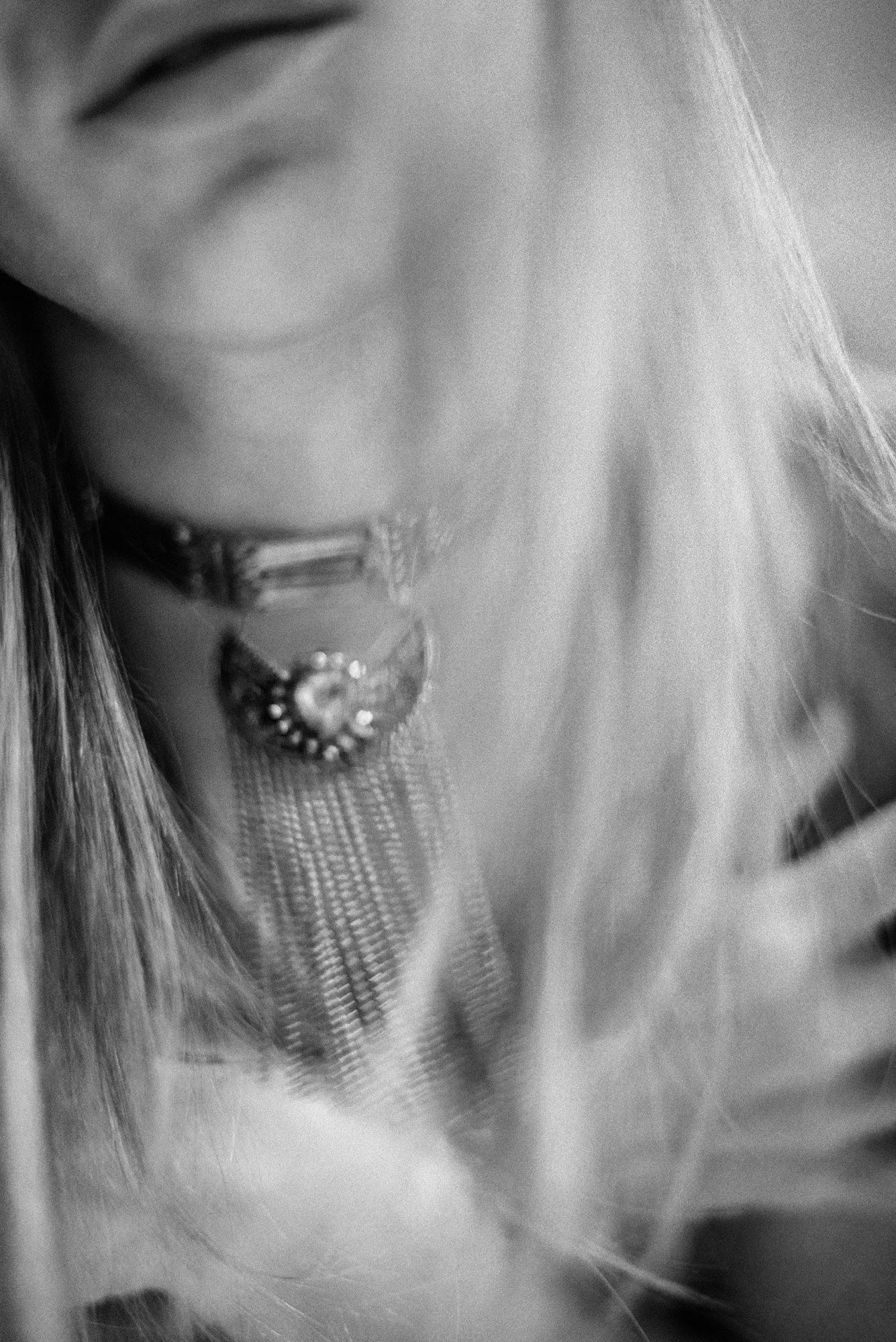 Abstract black-and-white close-up of neckline and statement necklace with soft motion blur.