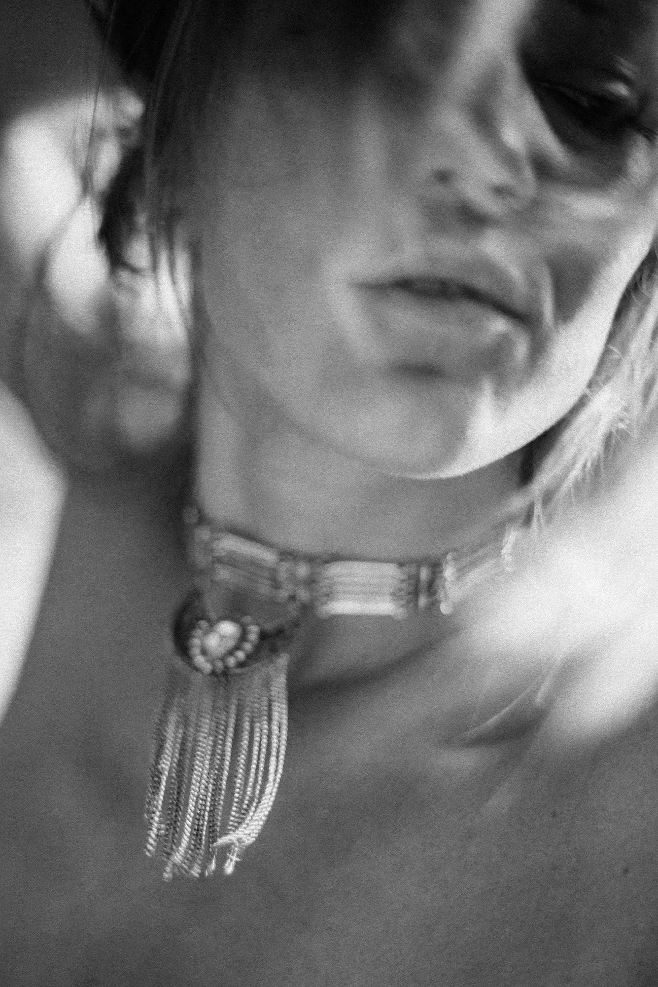 Blurred black-and-white close-up portrait with soft motion, partially obscured face and flowing hair.