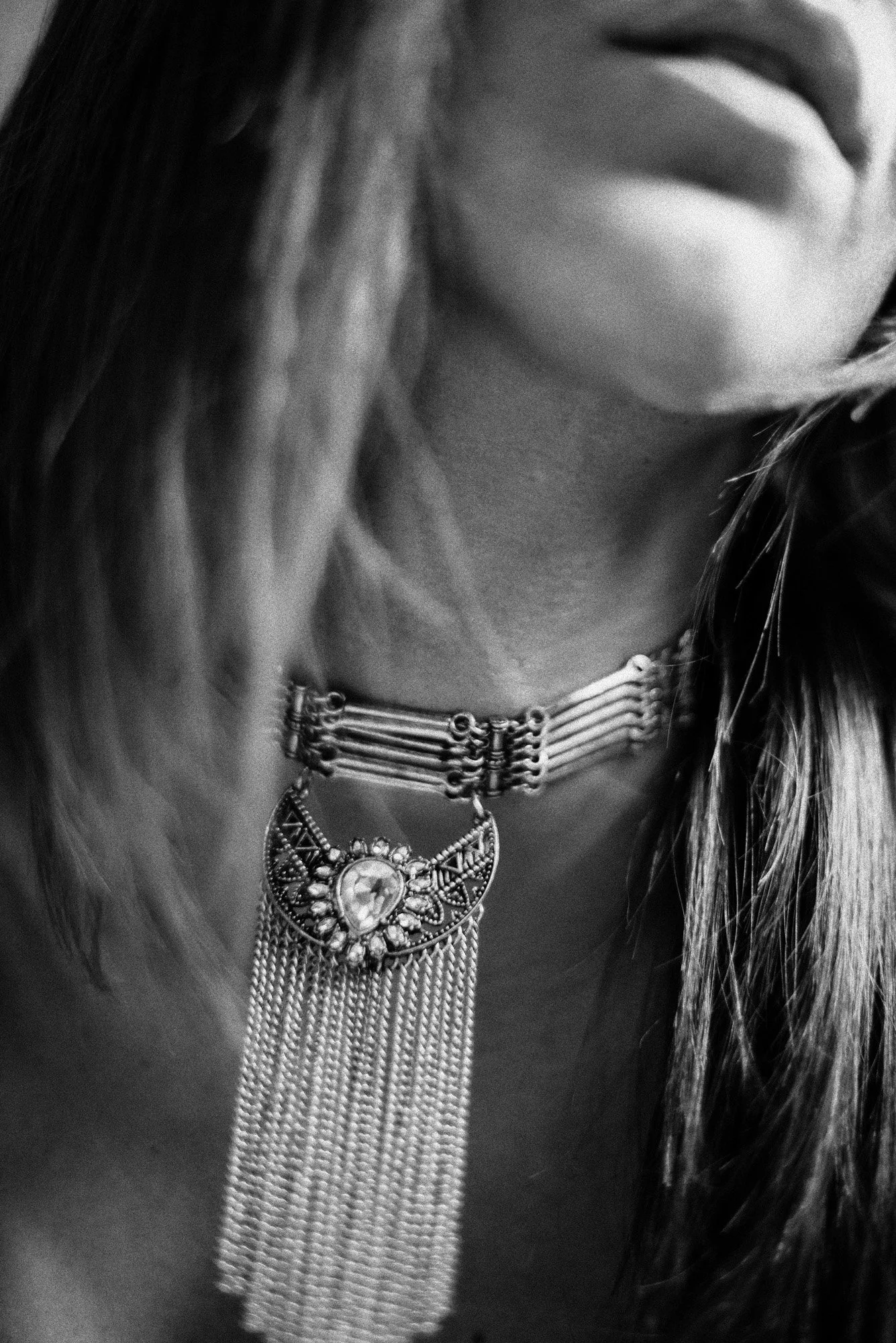 highly abstract black-and-white close-up of neckline and statement necklace with soft motion blur.