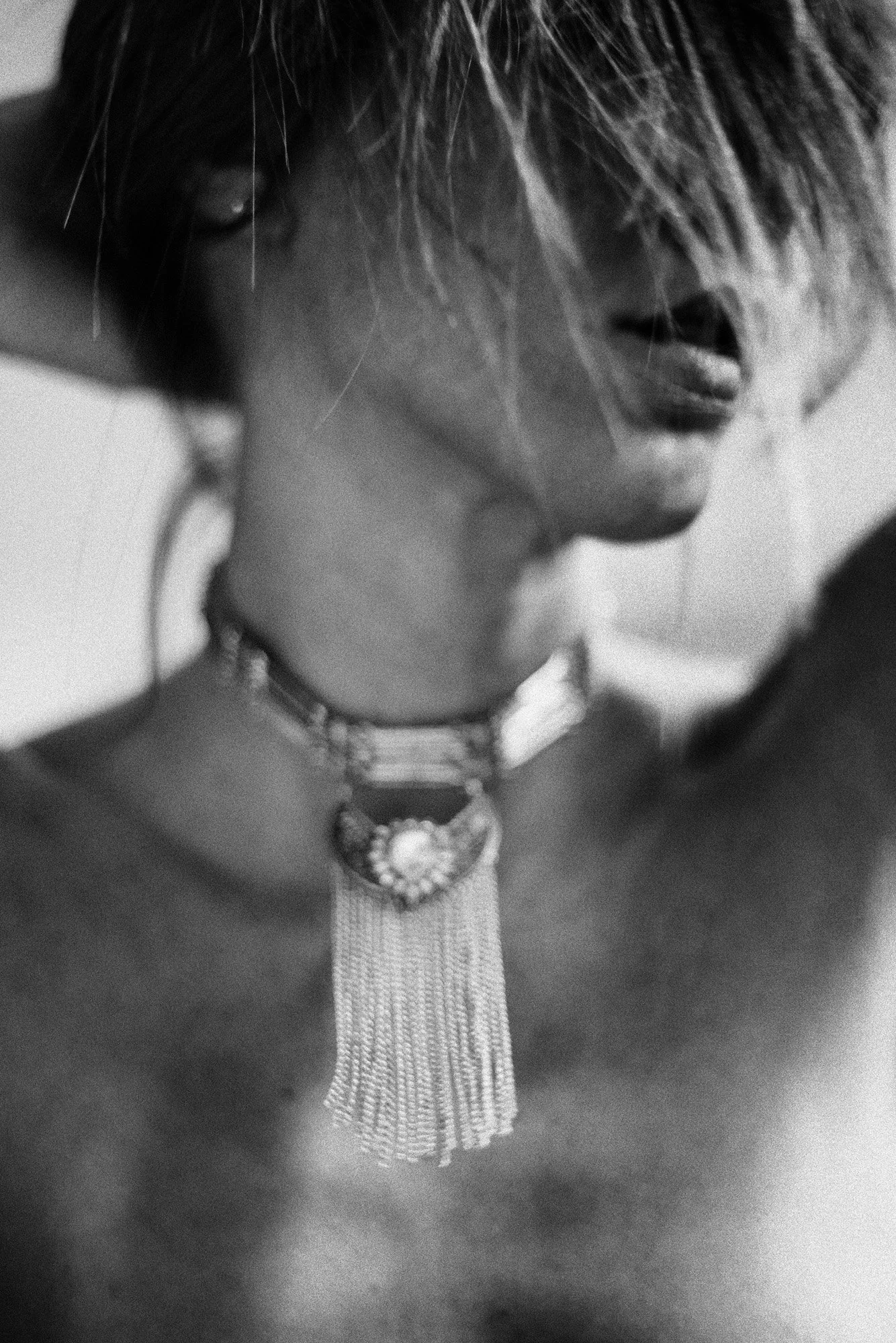 Abstract black-and-white close-up of collarbone and statement necklace with soft motion blur.