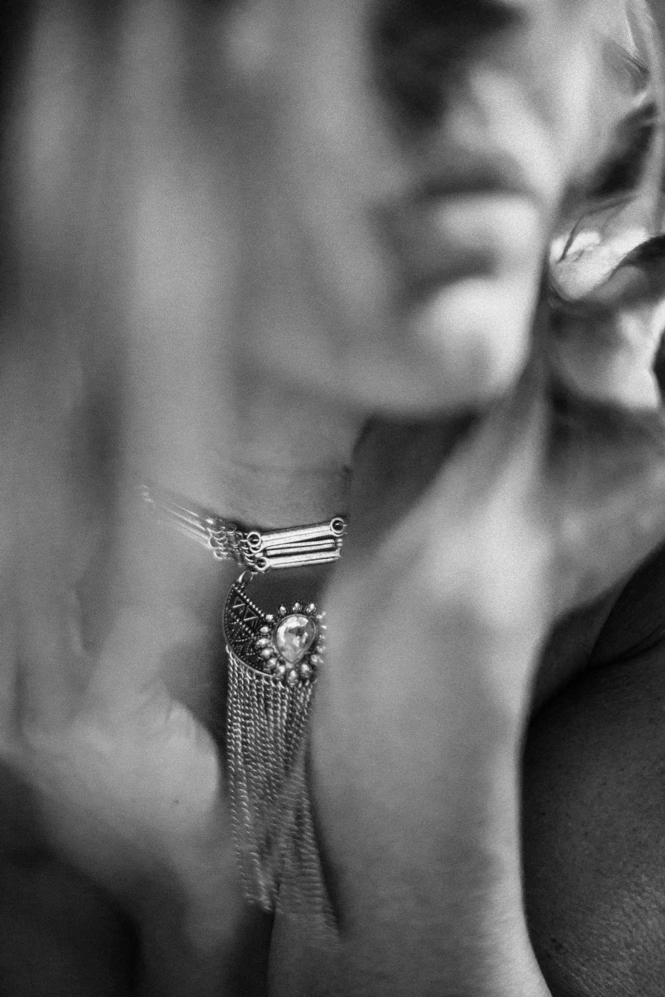 Abstract black-and-white close-up of neckline and statement necklace with soft motion blur.