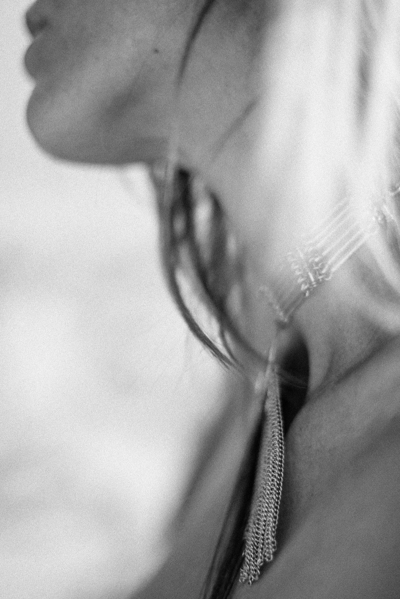 Minimal black-and-white portrait fragment showing jawline and neck in shallow focus.