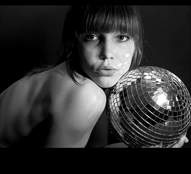 Close-up self-portrait with mirrored disco ball, black-and-white photography exploring reflection and identity
