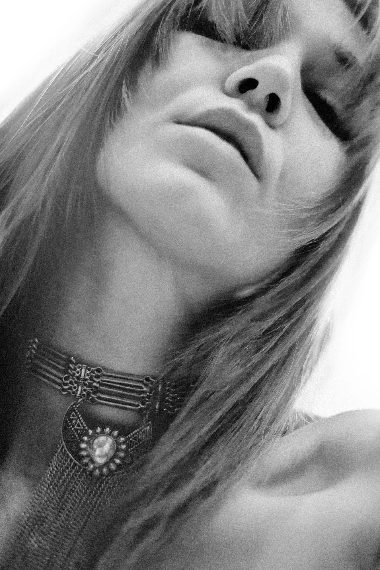 Minimal black-and-white portrait fragment showing jawline and neck in shallow focus.