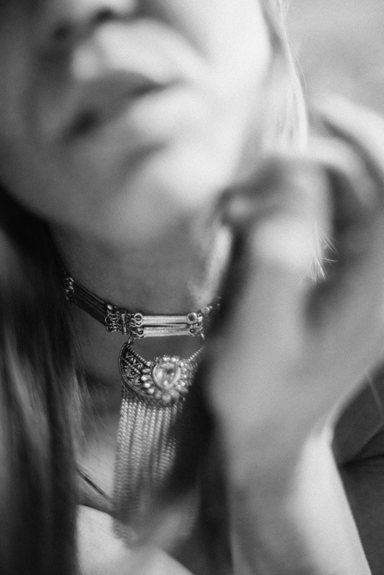 Blurred black-and-white close-up portrait with soft motion, partially obscured face and flowing hair.