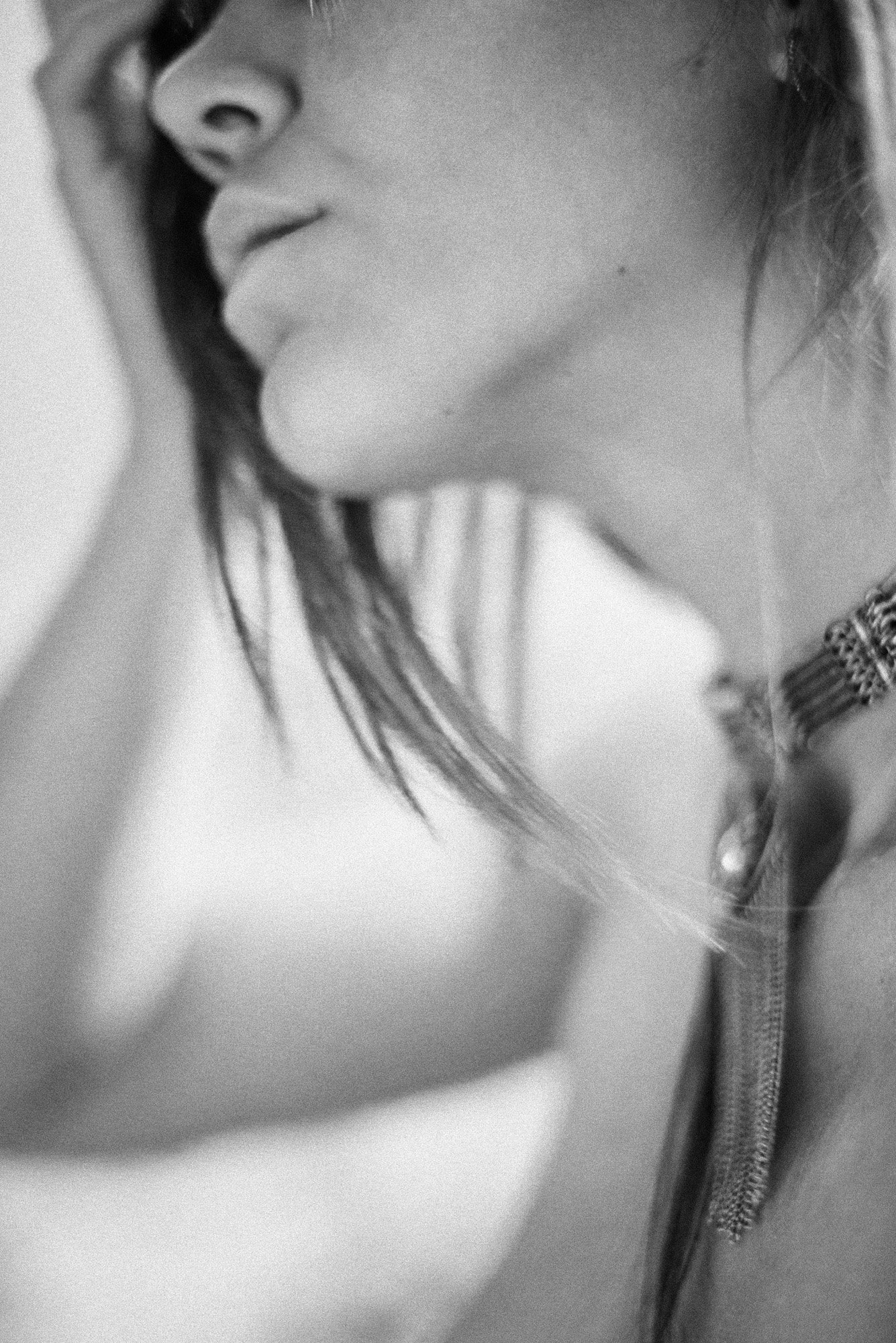 Blurred black-and-white close-up portrait with soft motion, partially obscured face and flowing hair.