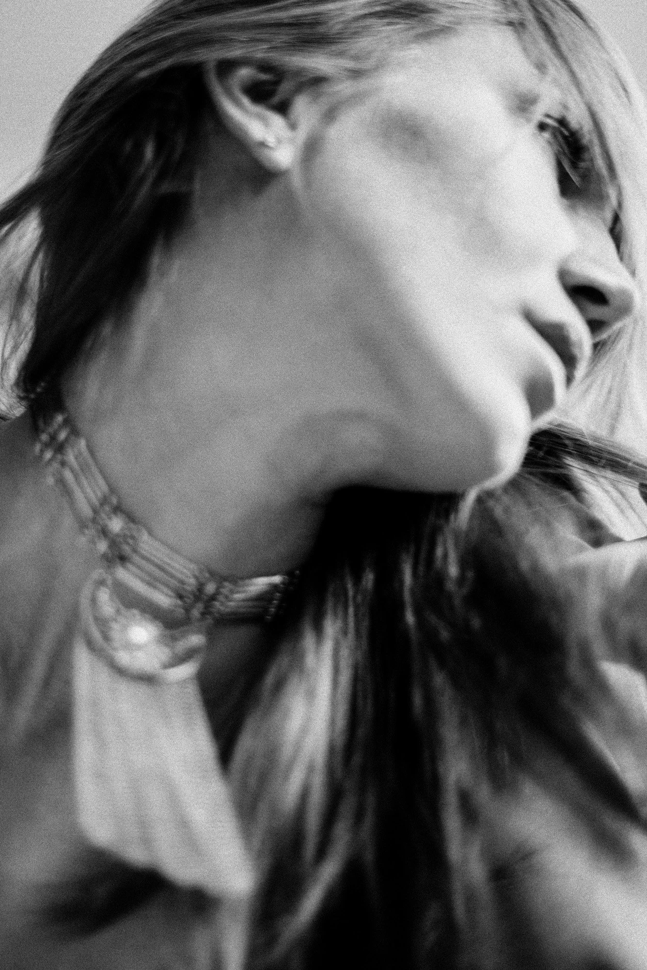 Minimal black-and-white portrait fragment showing jawline and neck in shallow focus.