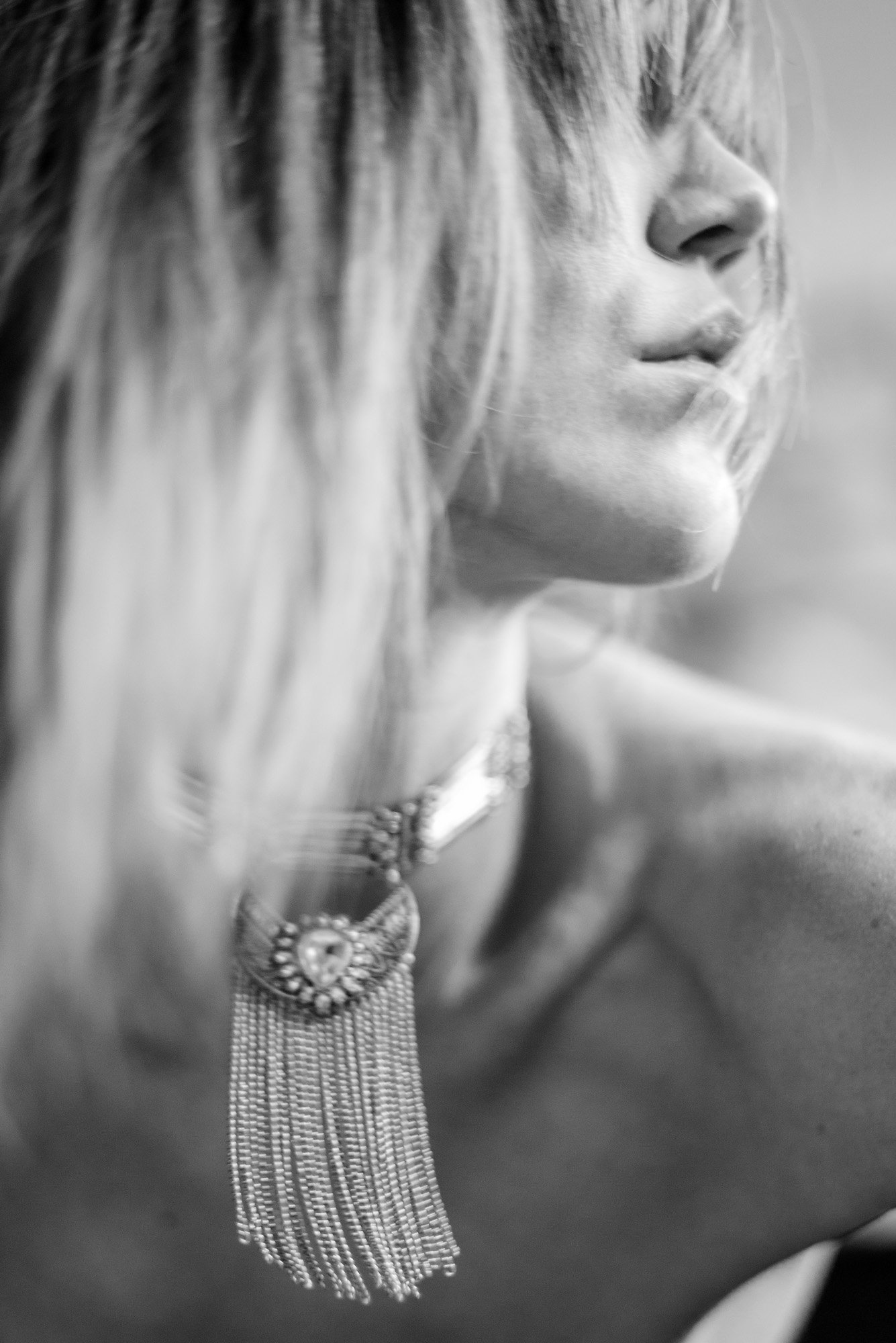highly abstract black-and-white close-up of neckline and statement necklace with soft motion blur.