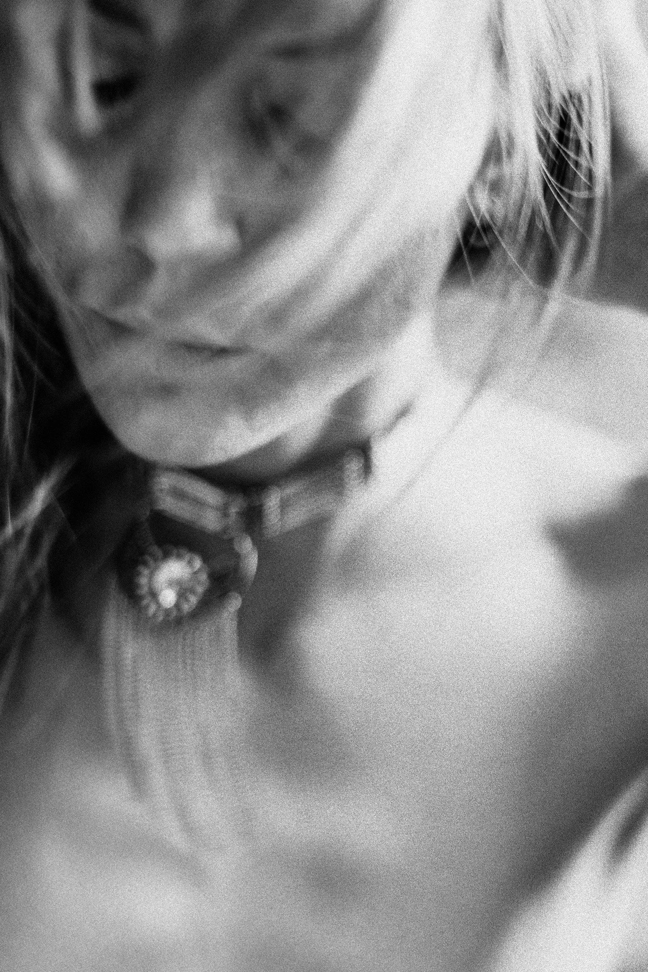 highly abstract black-and-white close-up of neckline and statement necklace with soft motion blur.