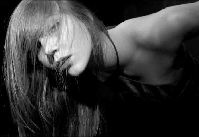 Low-light self-portrait emphasizing texture, shadow, and emotional stillness