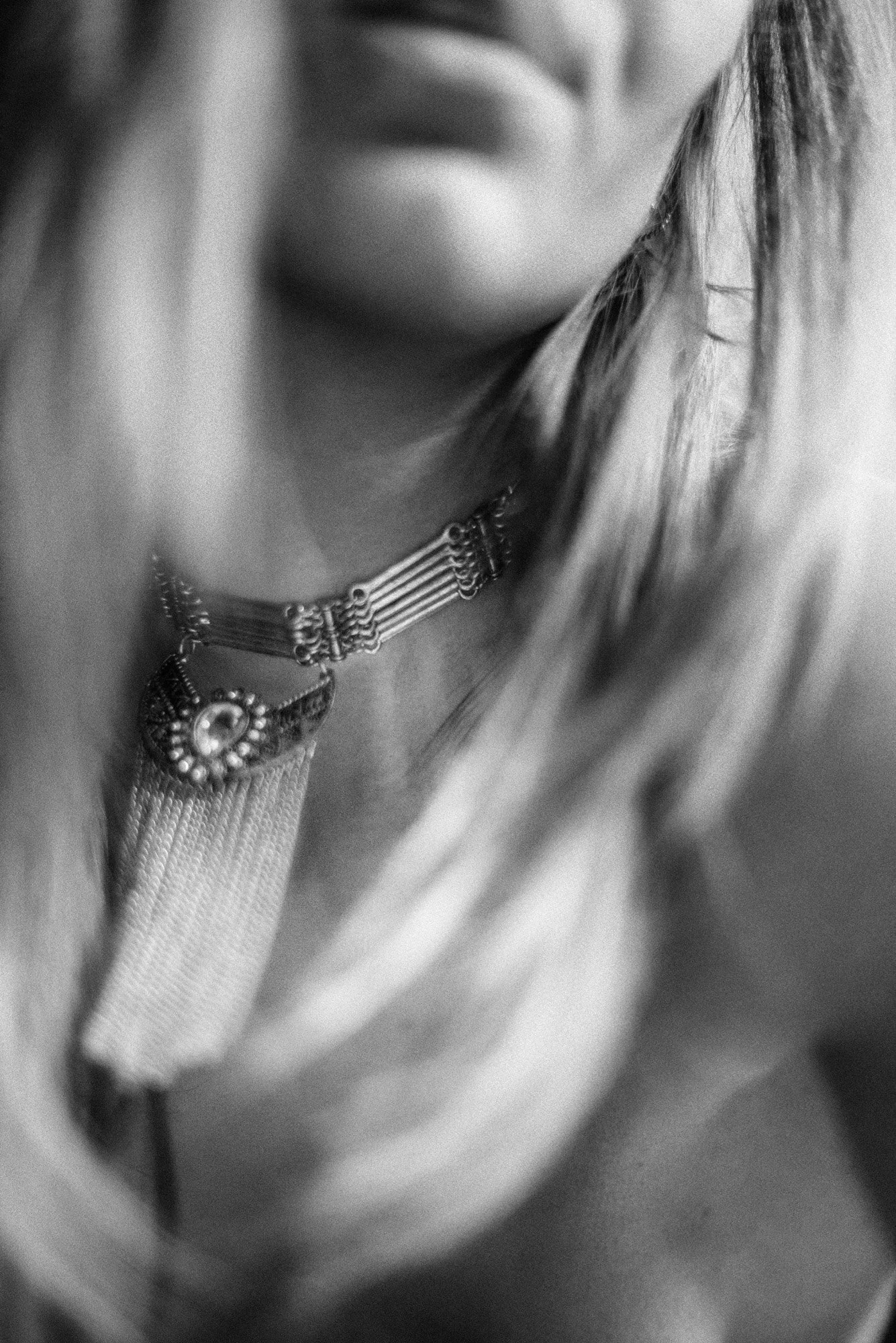 Abstract black-and-white close-up of neckline and statement necklace with soft motion blur.