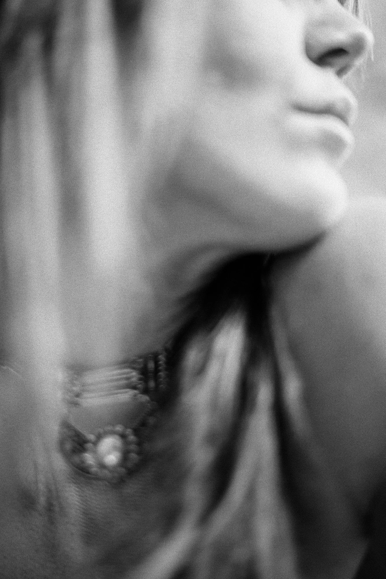 highly abstract black-and-white close-up of neckline and statement necklace with soft motion blur.
