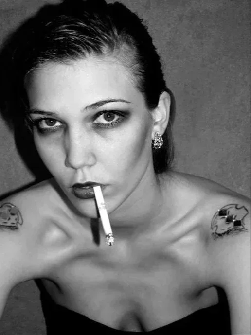 Black and white self-portrait of Lou Vicious from early work, confronting the camera with a direct gaze and cigarette — an image reflecting origin, rebellion and self-authorship.