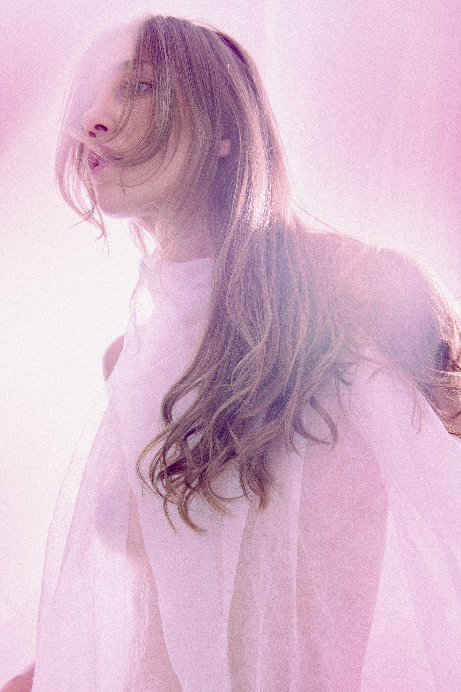 Soft, ethereal fine-art self-portrait of a woman in soft pastel light, partially veiled in fabric, expressing calm, presence, and emotional freedom.