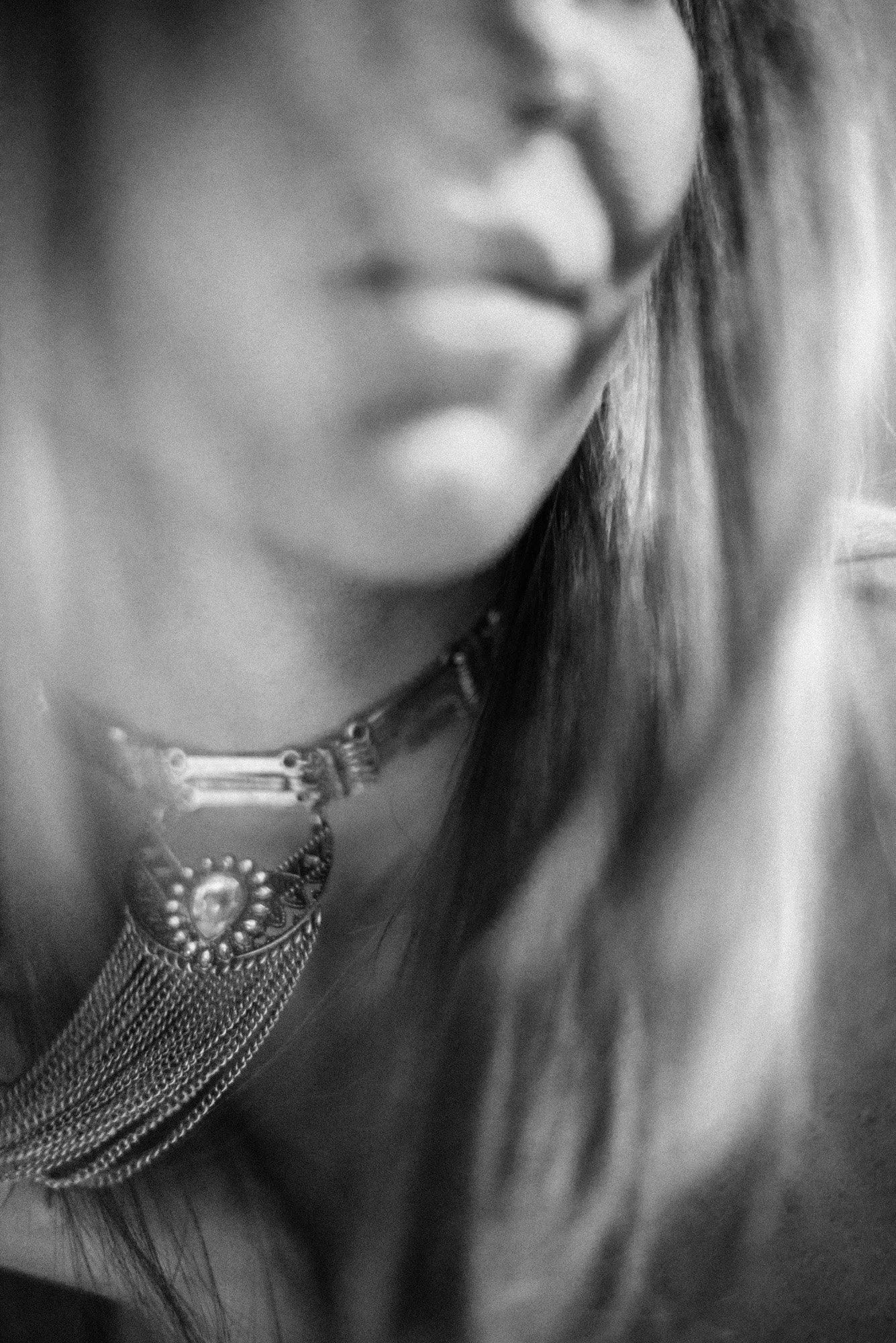 Abstract black-and-white close-up of neckline and statement necklace with soft motion blur.