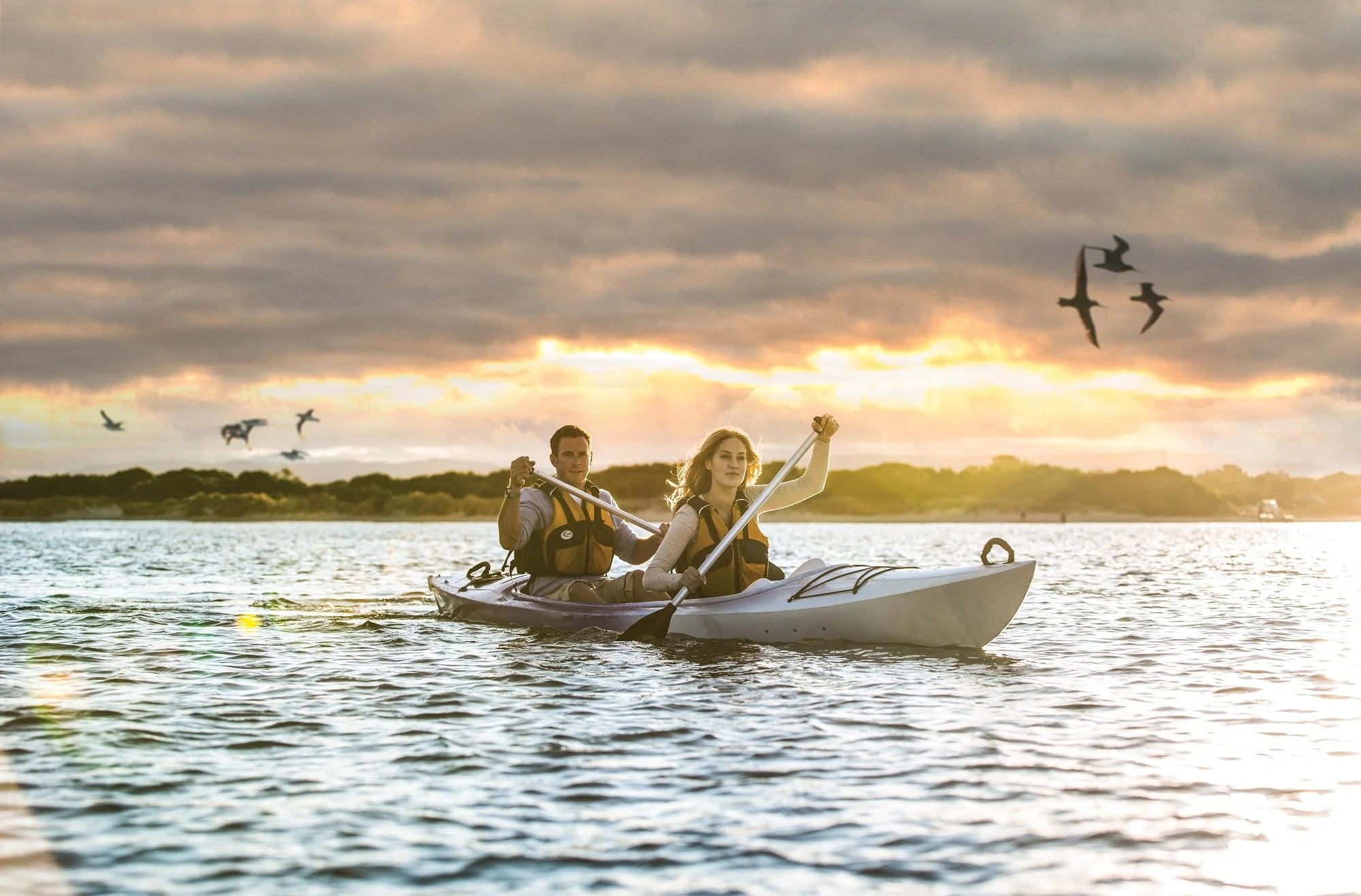 Saphire Freycinet, mies ja nainen kajakkiretkellä auringonlaskun aikaan upeassa Wineglass Bayssa.